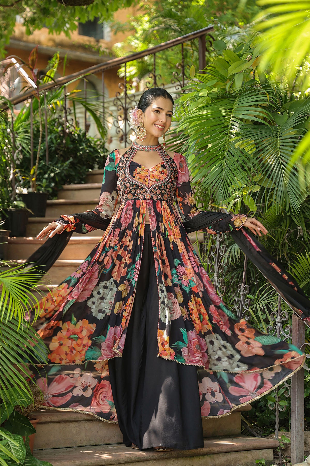 Woman in a floral dress standing on steps surrounded by greenery