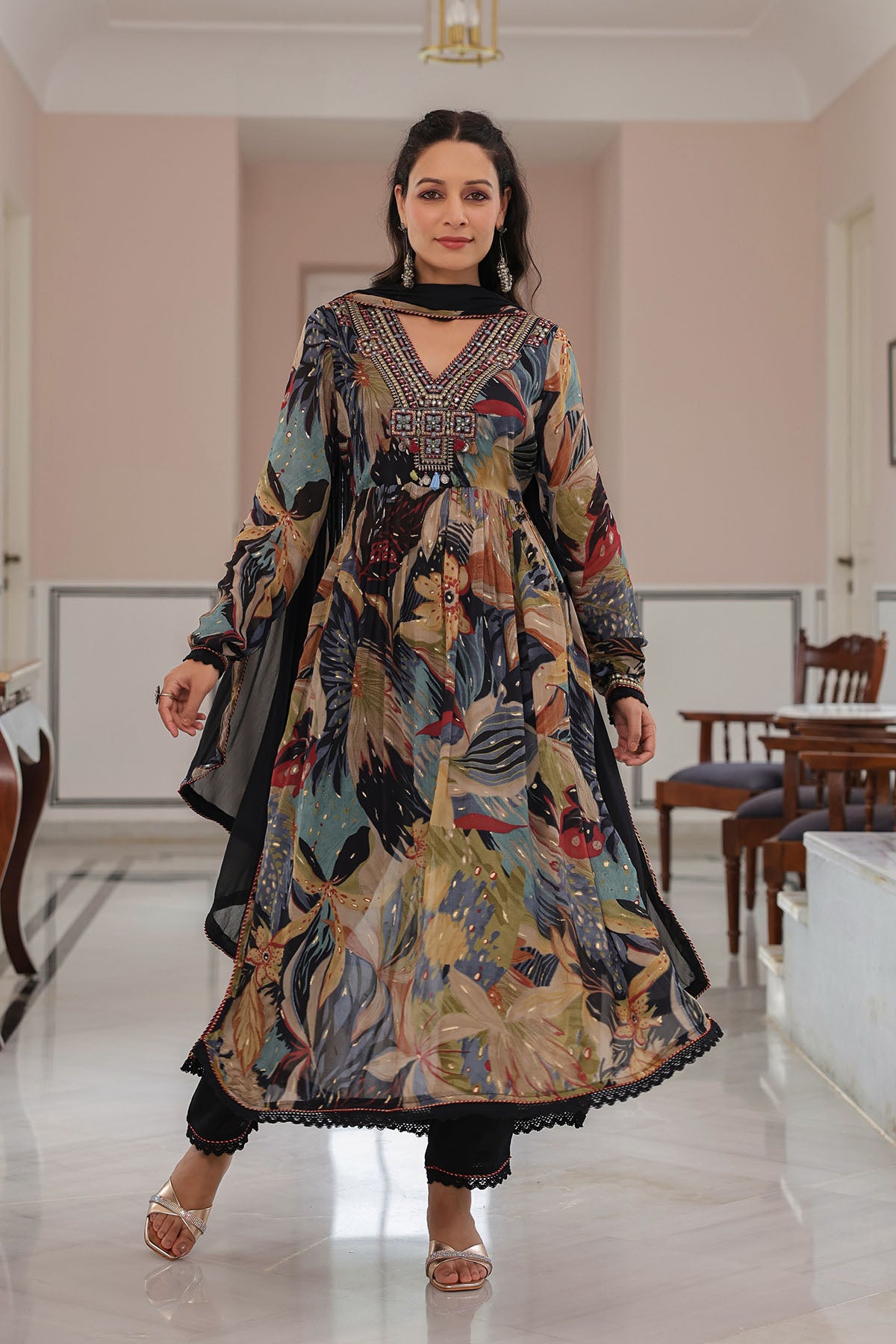 Woman wearing a long, patterned dress in a room with tables and chairs.