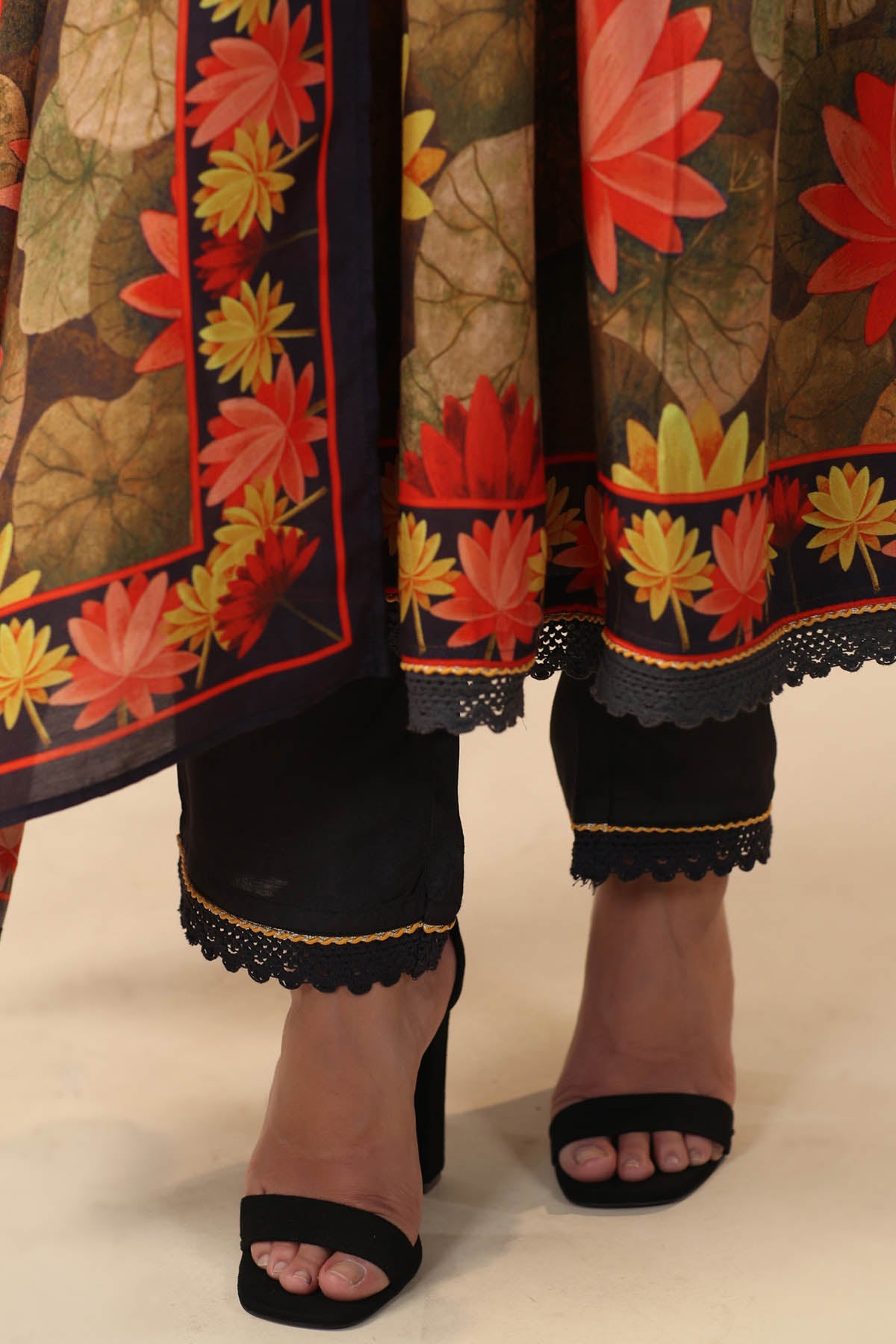 Traditional outfit with floral patterns and black shoes on a neutral background