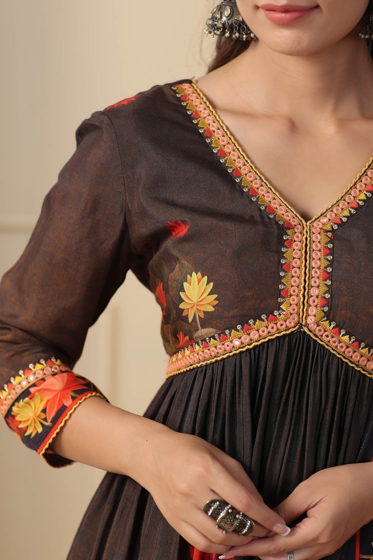Close-up of a dark brown dress with colorful embroidery on a neutral background