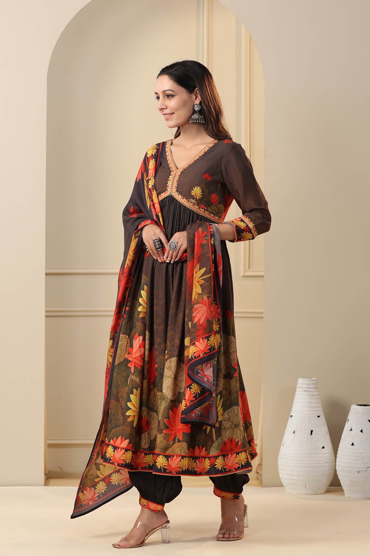 Woman wearing a traditional outfit with floral patterns in a neutral setting