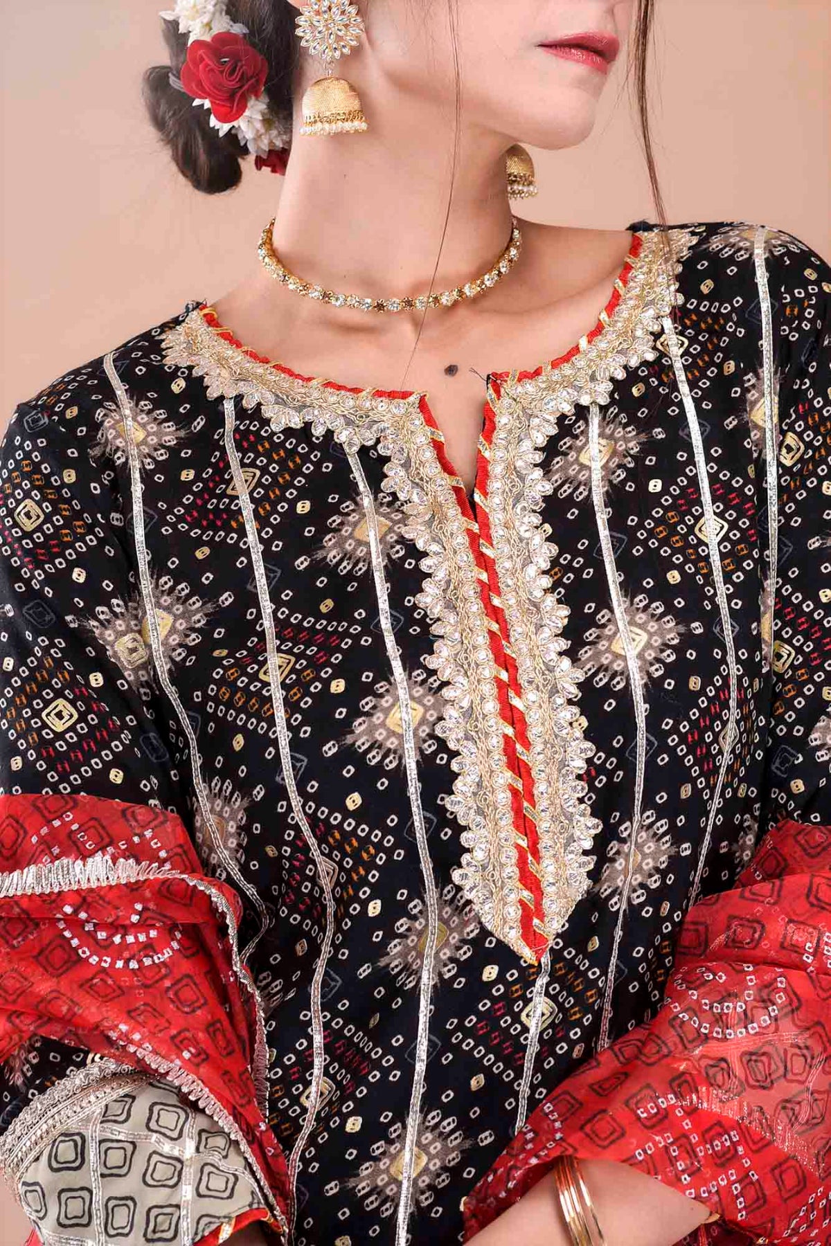 Close-up of a person wearing a black and red embroidered traditional outfit with gold jewelry.