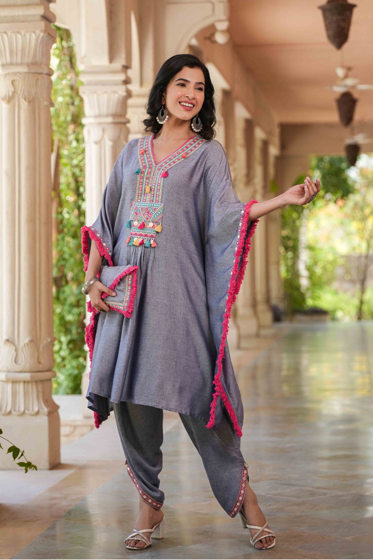 Woman in traditional outfit with colorful embroidery standing in a decorative hallway.