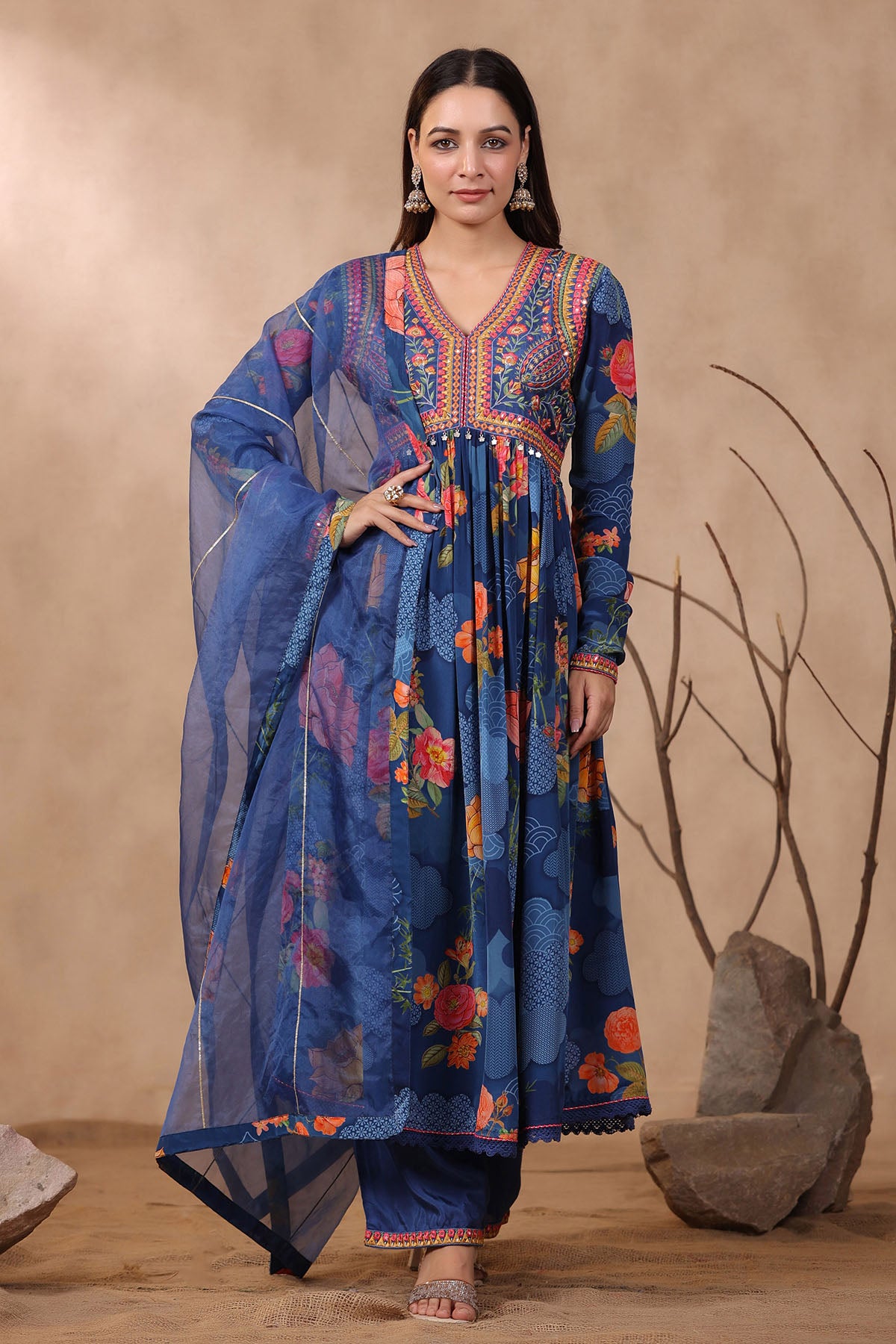 Woman wearing a colorful traditional outfit with a blue floral design against a beige background