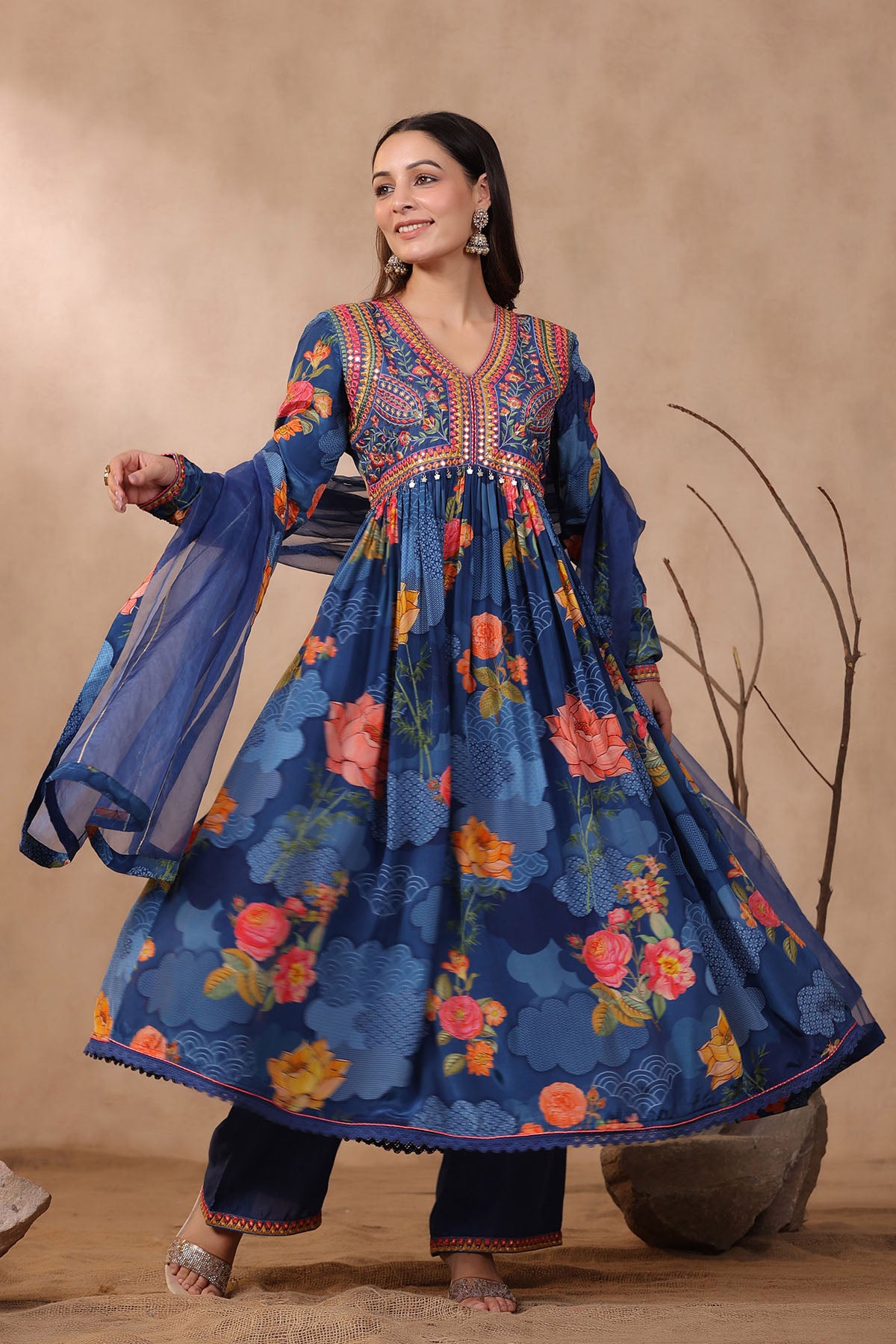 Woman wearing a blue floral dress with embroidery against a beige background