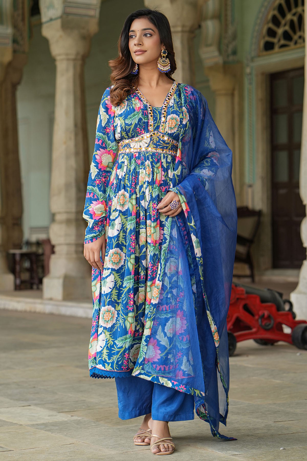 Woman in a colorful traditional outfit standing in an outdoor setting.
