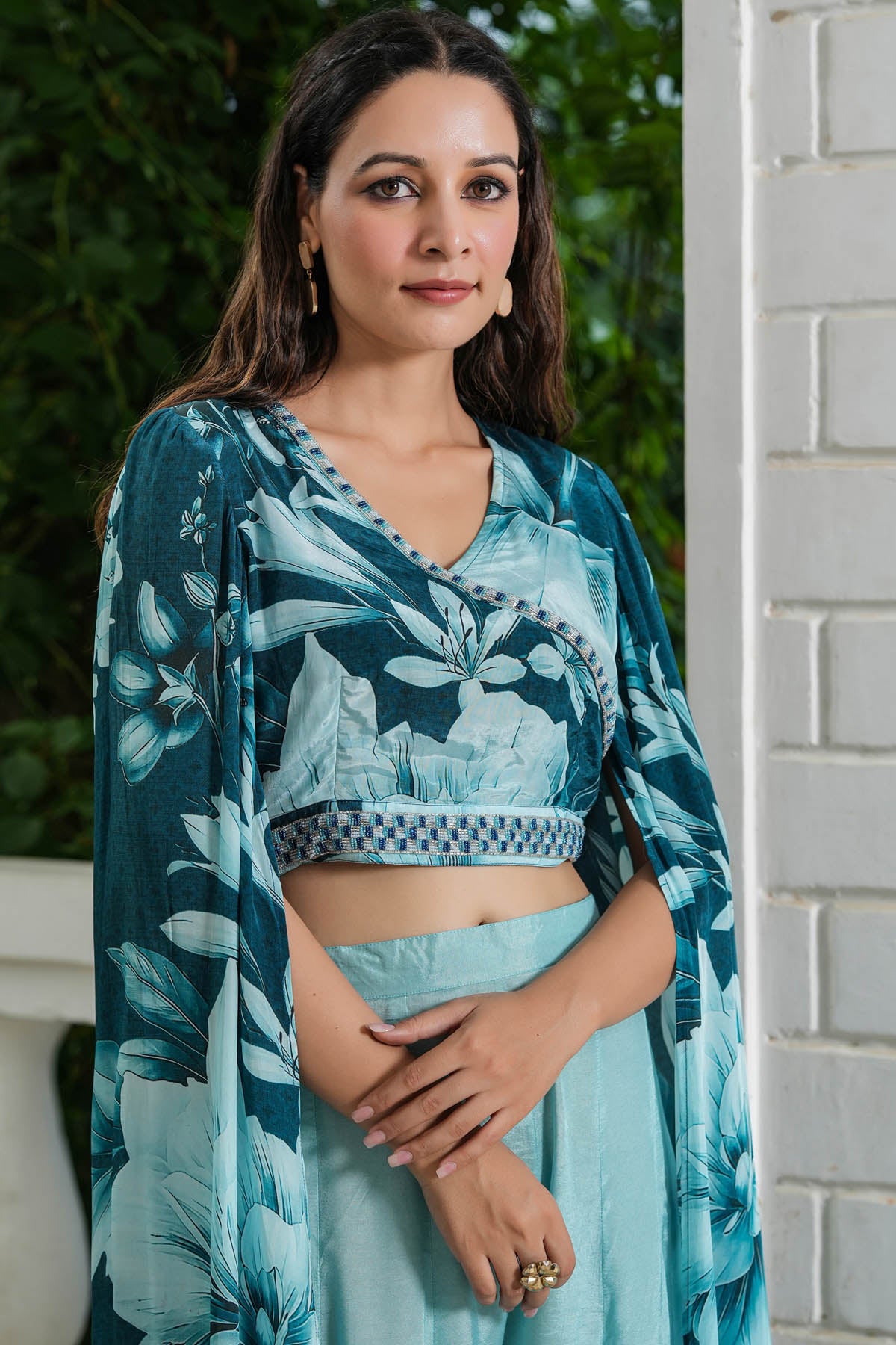 Woman wearing a teal floral outfit standing outdoors.