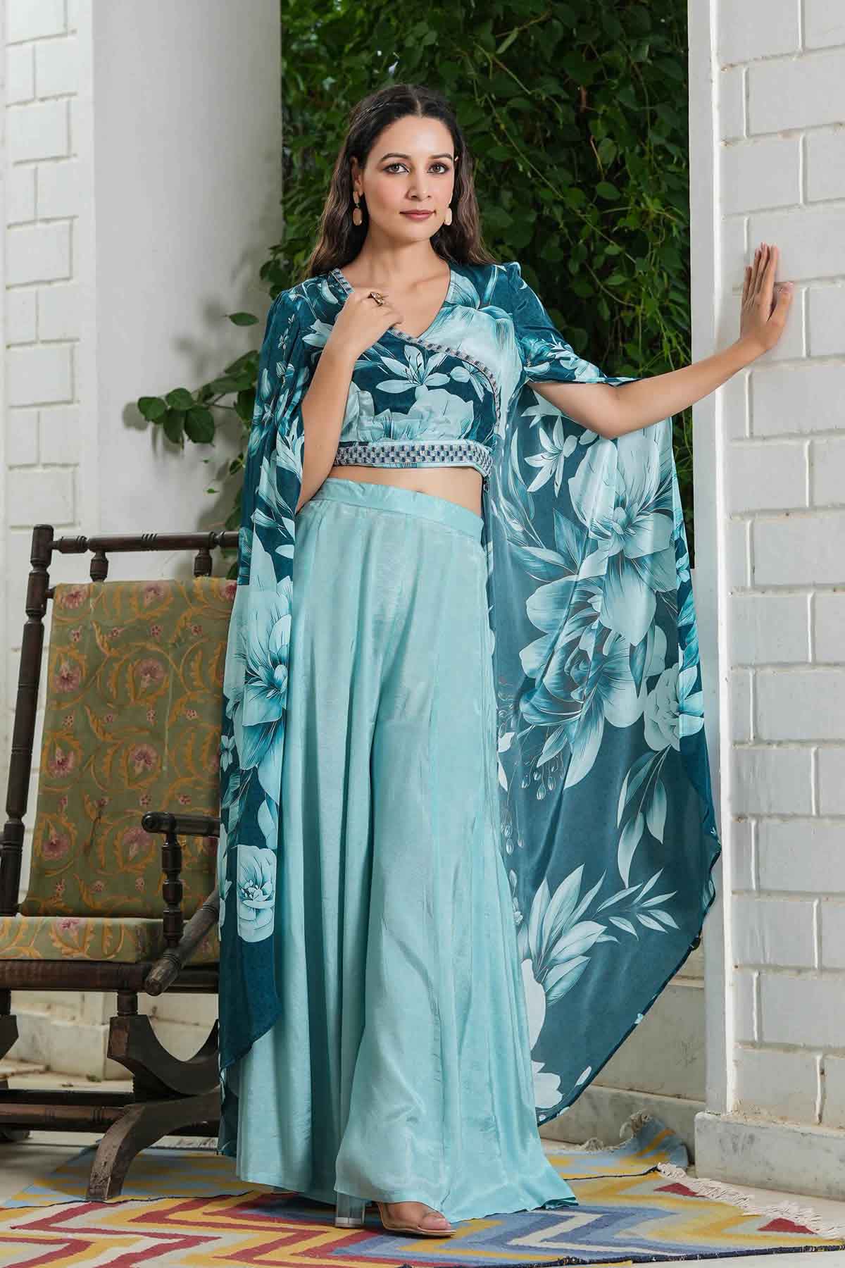 Woman wearing a teal floral outfit standing in a doorway.