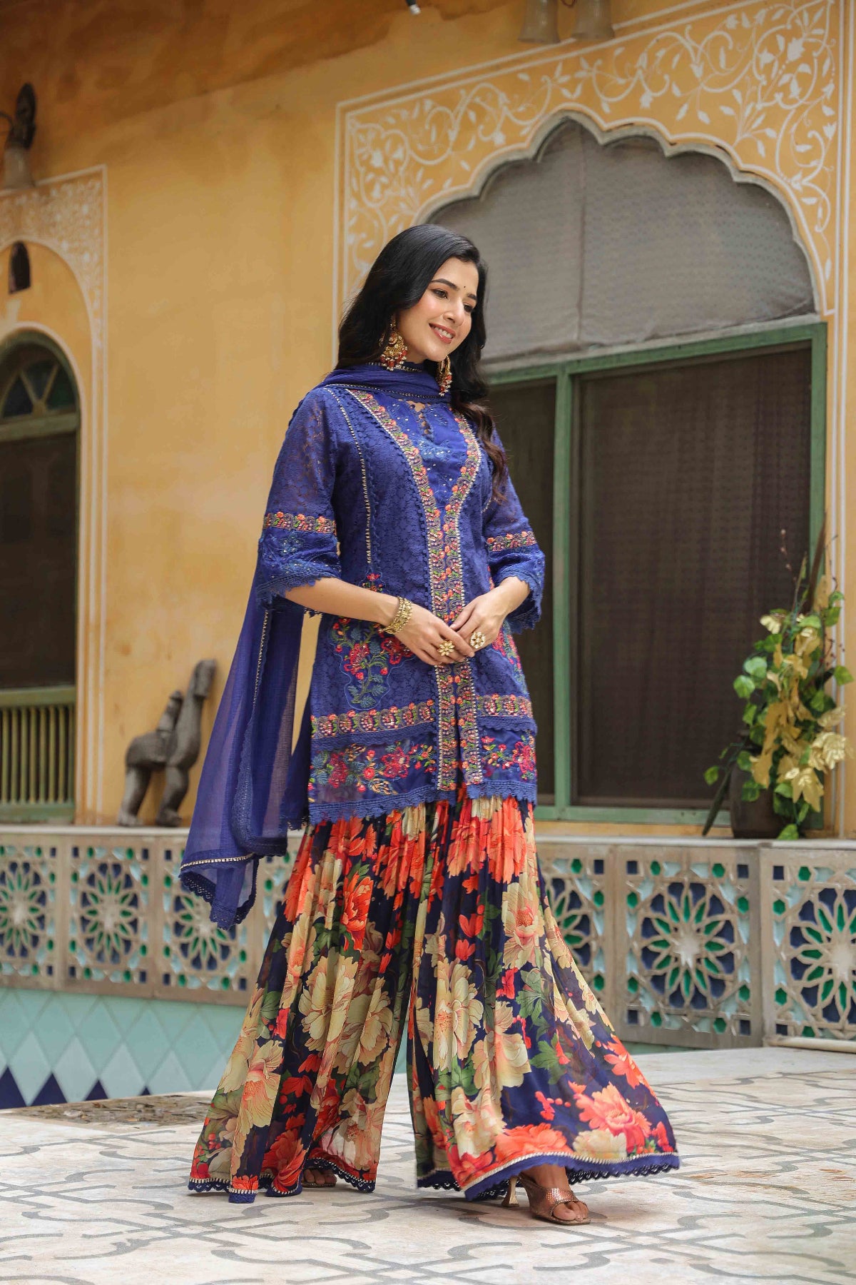 Woman in a traditional outfit standing in front of a decorative building.