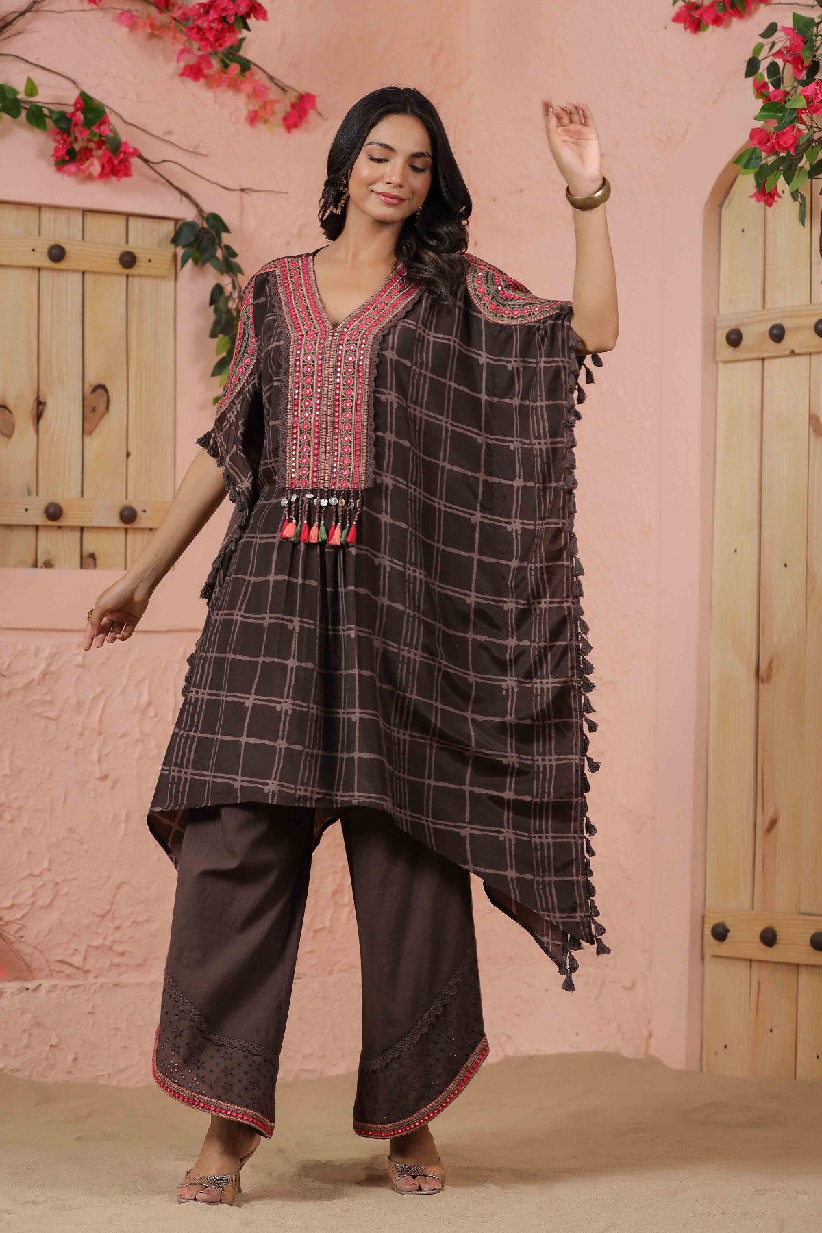 Woman wearing a traditional outfit with a checkered design in a decorative setting.