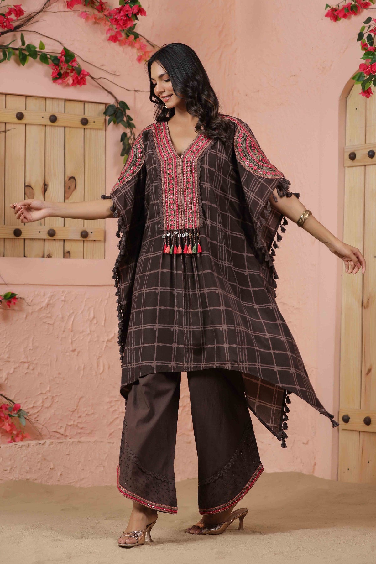Woman wearing a traditional outfit with a checkered pattern in a decorative setting.