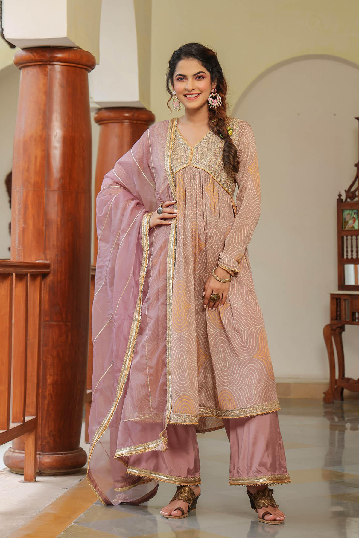 Woman in a traditional pink and gold outfit standing in an indoor setting.