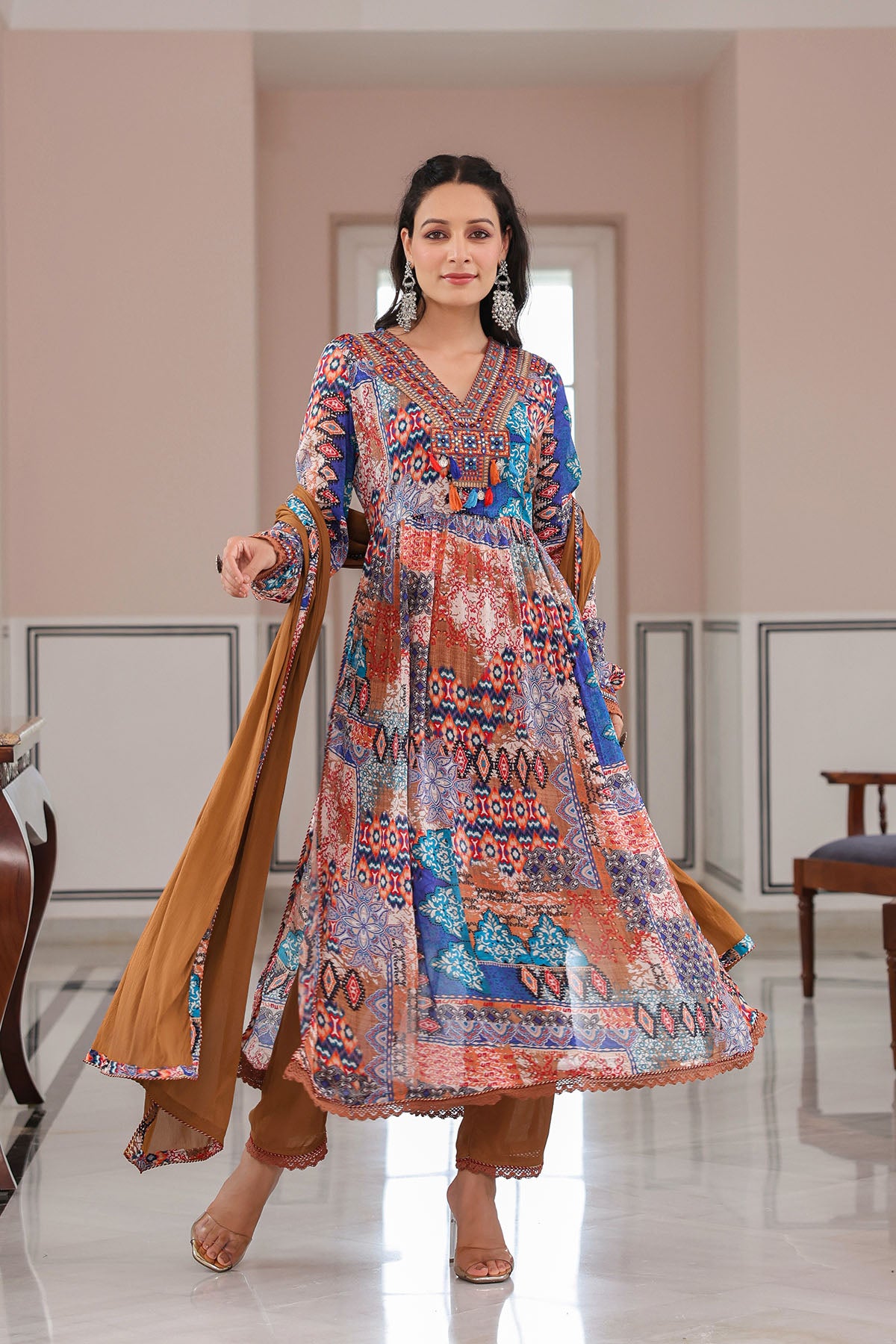 Woman wearing a colorful traditional outfit in a room with a mirror.