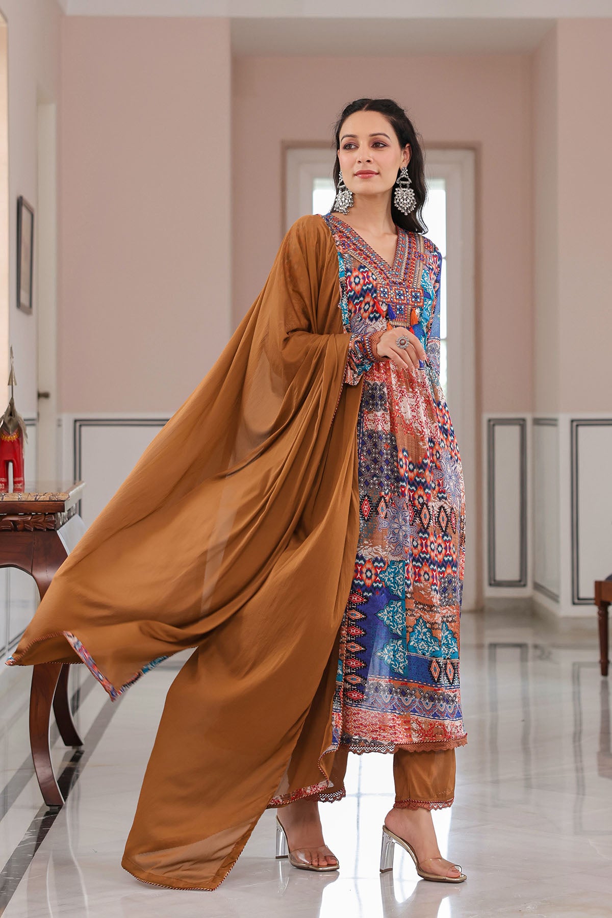 Woman wearing a traditional outfit with a long brown dupatta in a well-lit room.