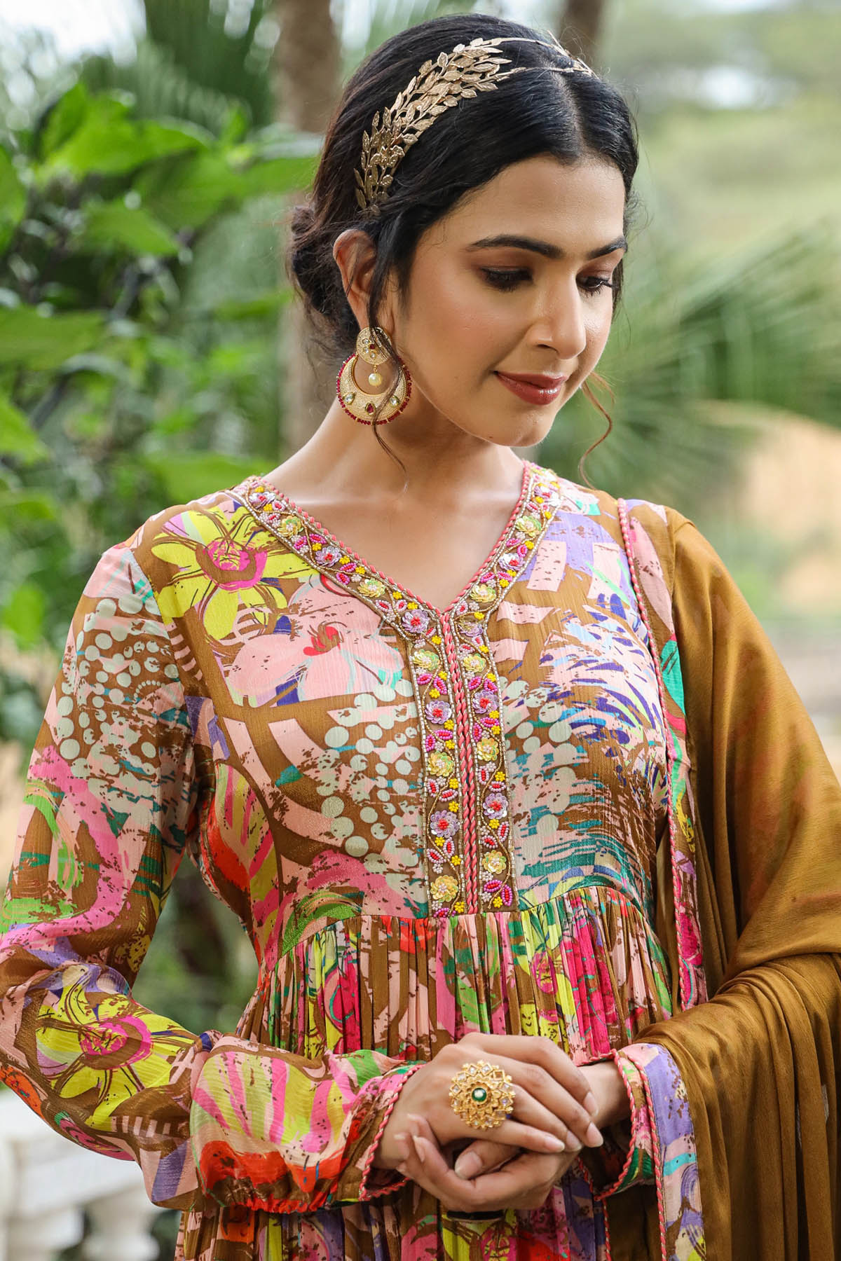 Woman wearing a colorful traditional outfit with a headband and earrings, standing outdoors.