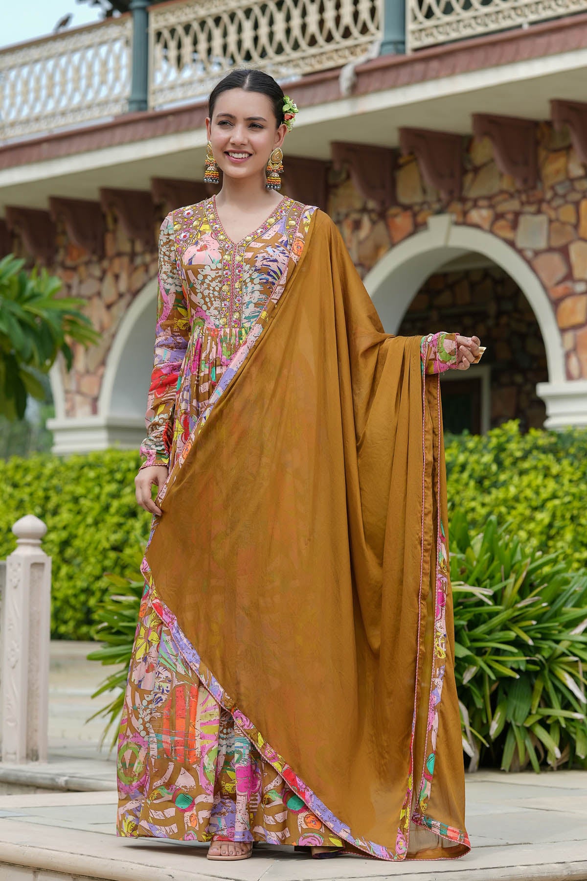 Woman in traditional outfit with a brown saree and colorful blouse in an outdoor setting.