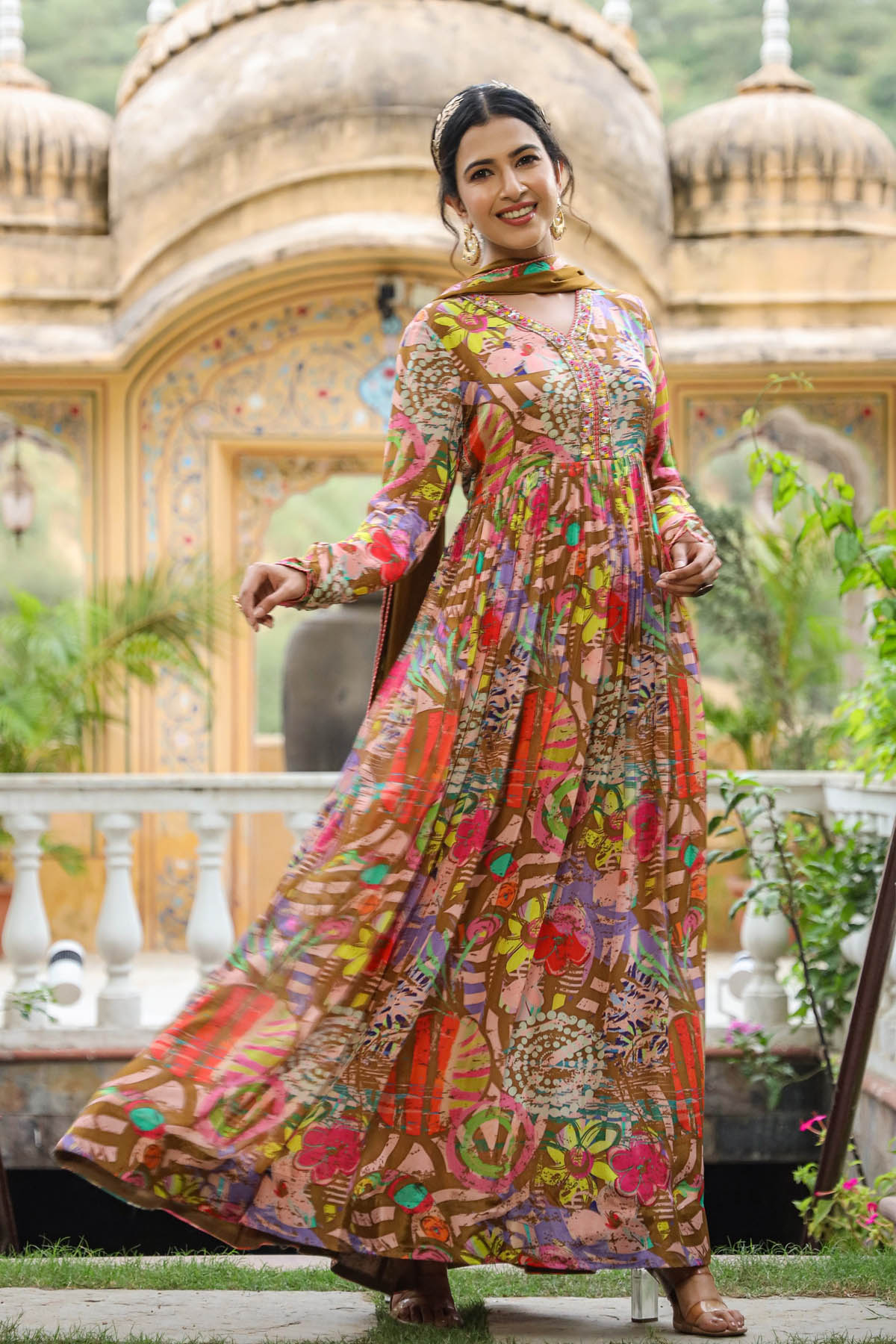 Woman in a colorful patterned dress standing in front of an ornate building.