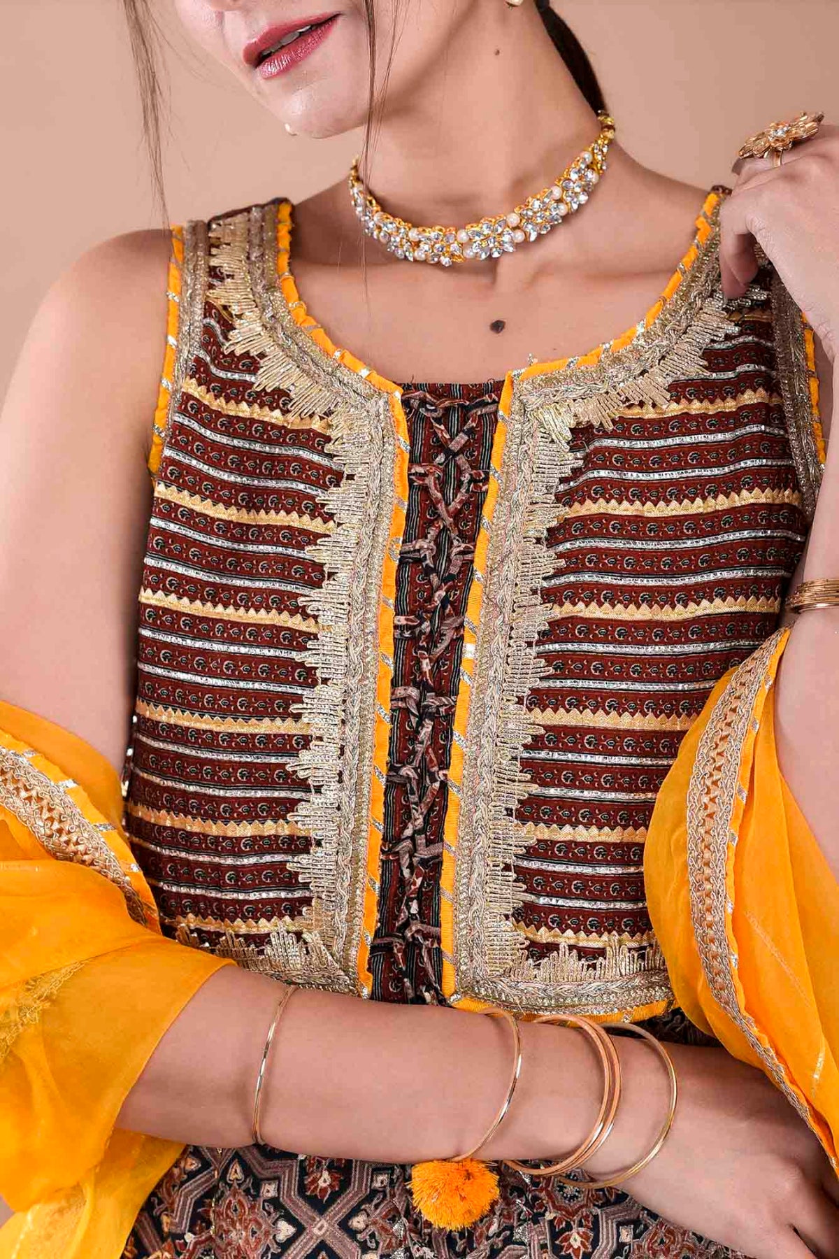 Close-up of a person wearing a patterned top with yellow accents and jewelry.
