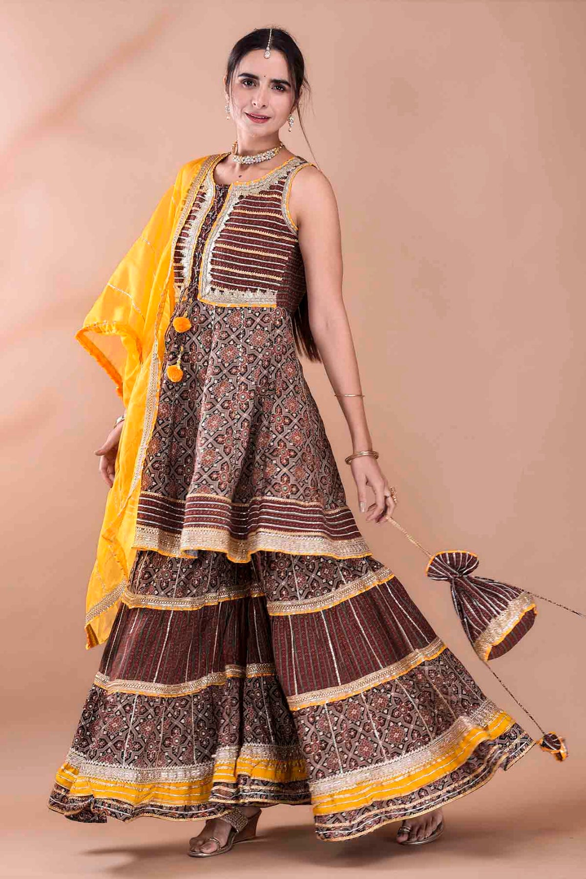 Woman wearing a traditional outfit with a brown and yellow pattern on a beige background