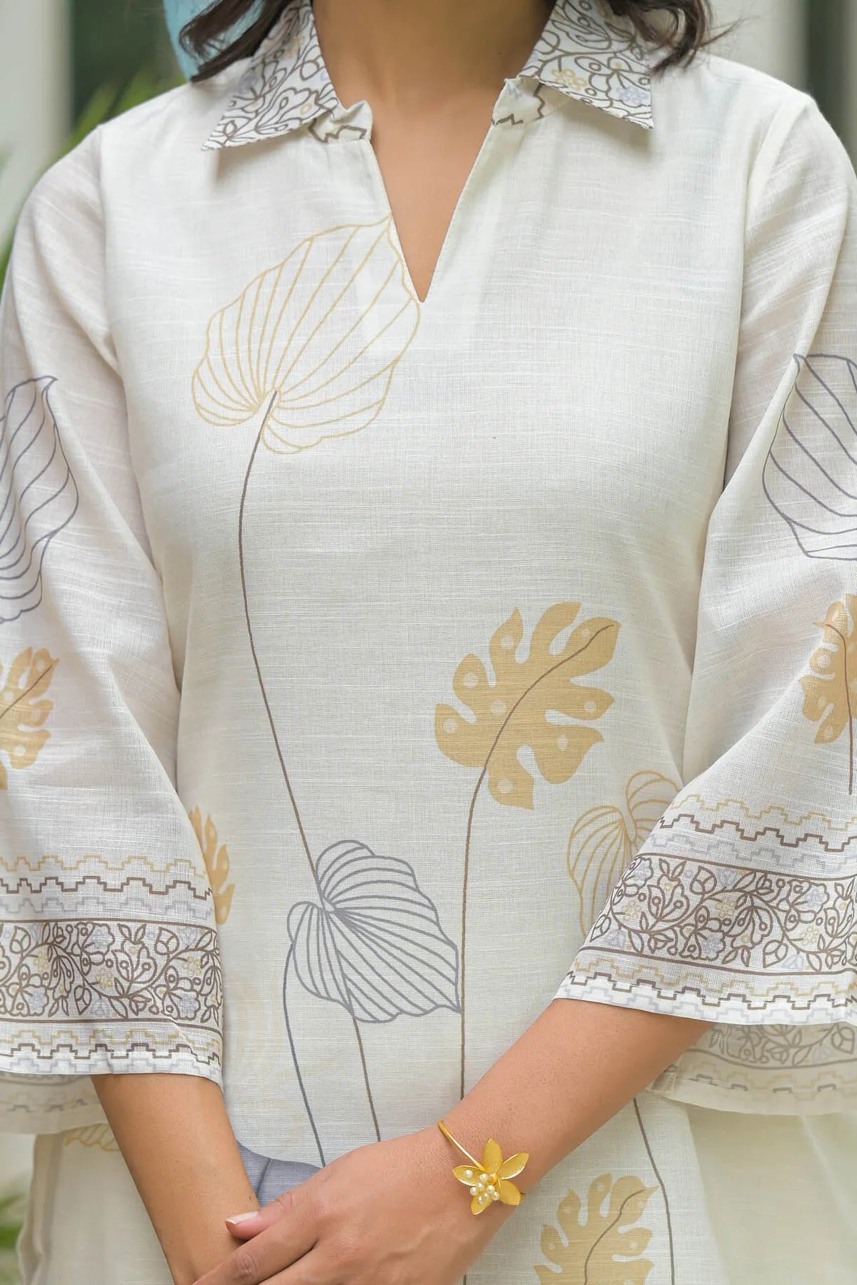White outfit with floral embroidery and a yellow flower bracelet.