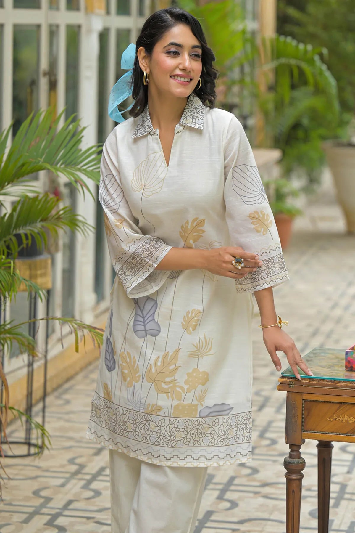 Woman in a white embroidered kurta with floral patterns standing outdoors.