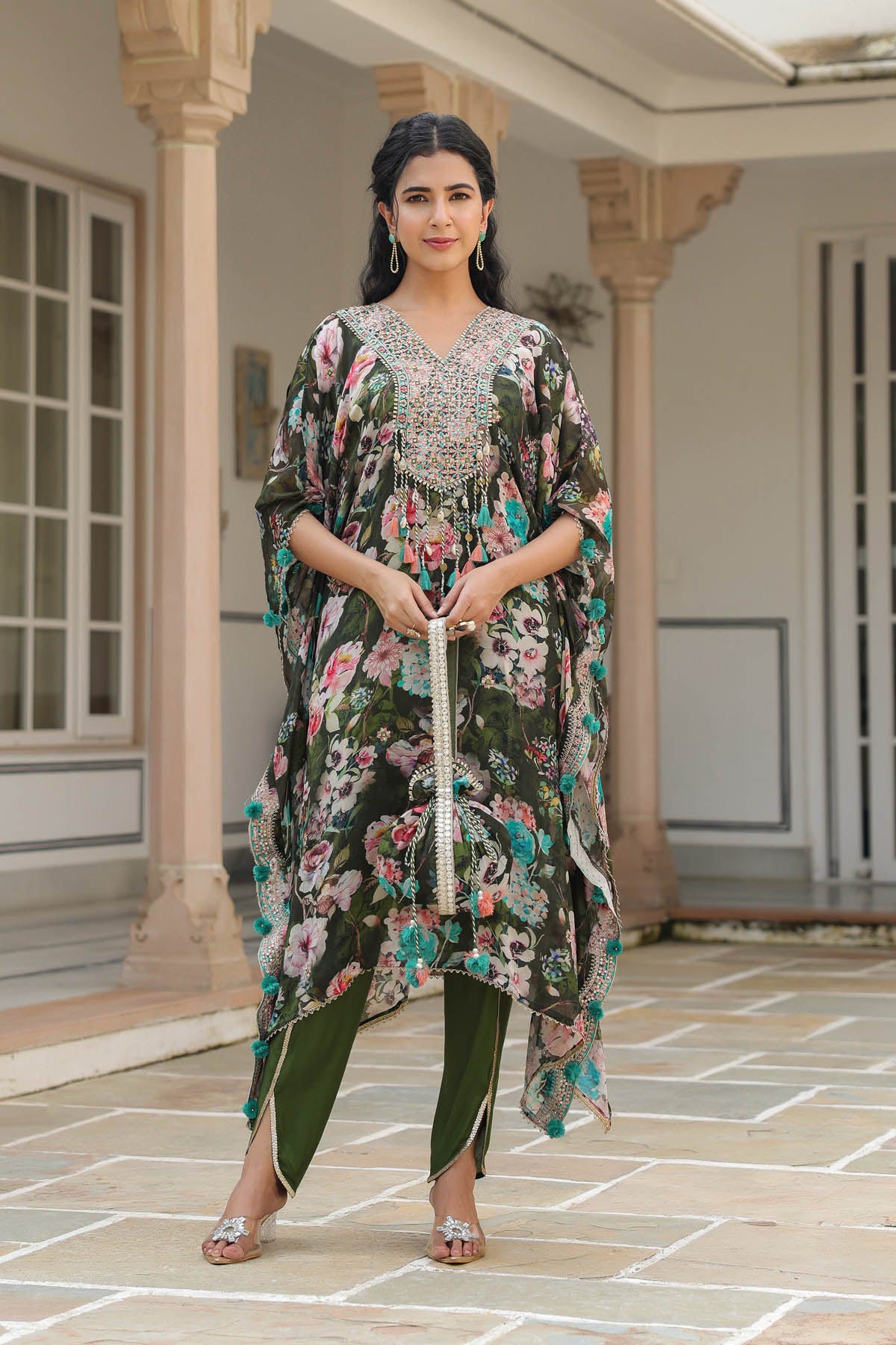 Woman in a floral dress standing in an indoor setting with columns.