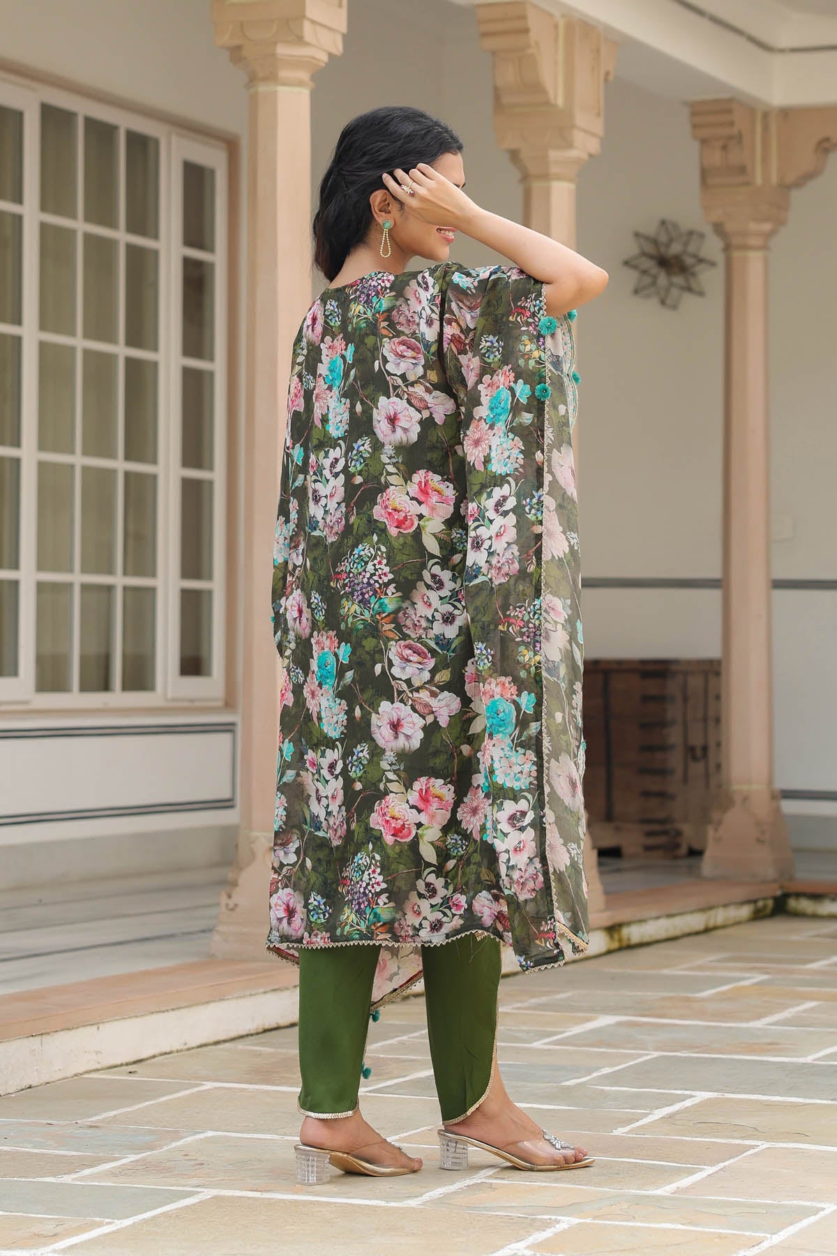 Woman wearing a floral dress standing in front of a building entrance.