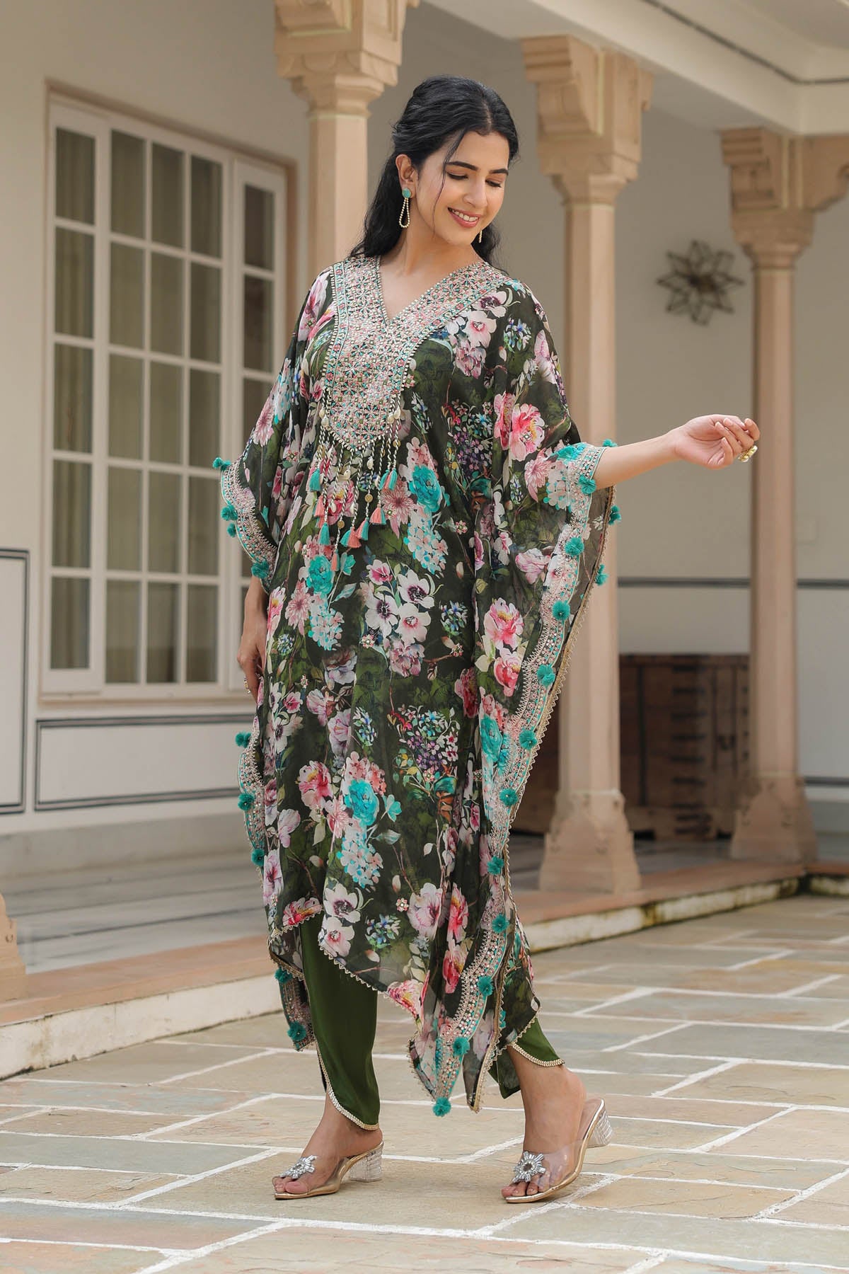 Woman in a floral dress standing in front of a building with columns.