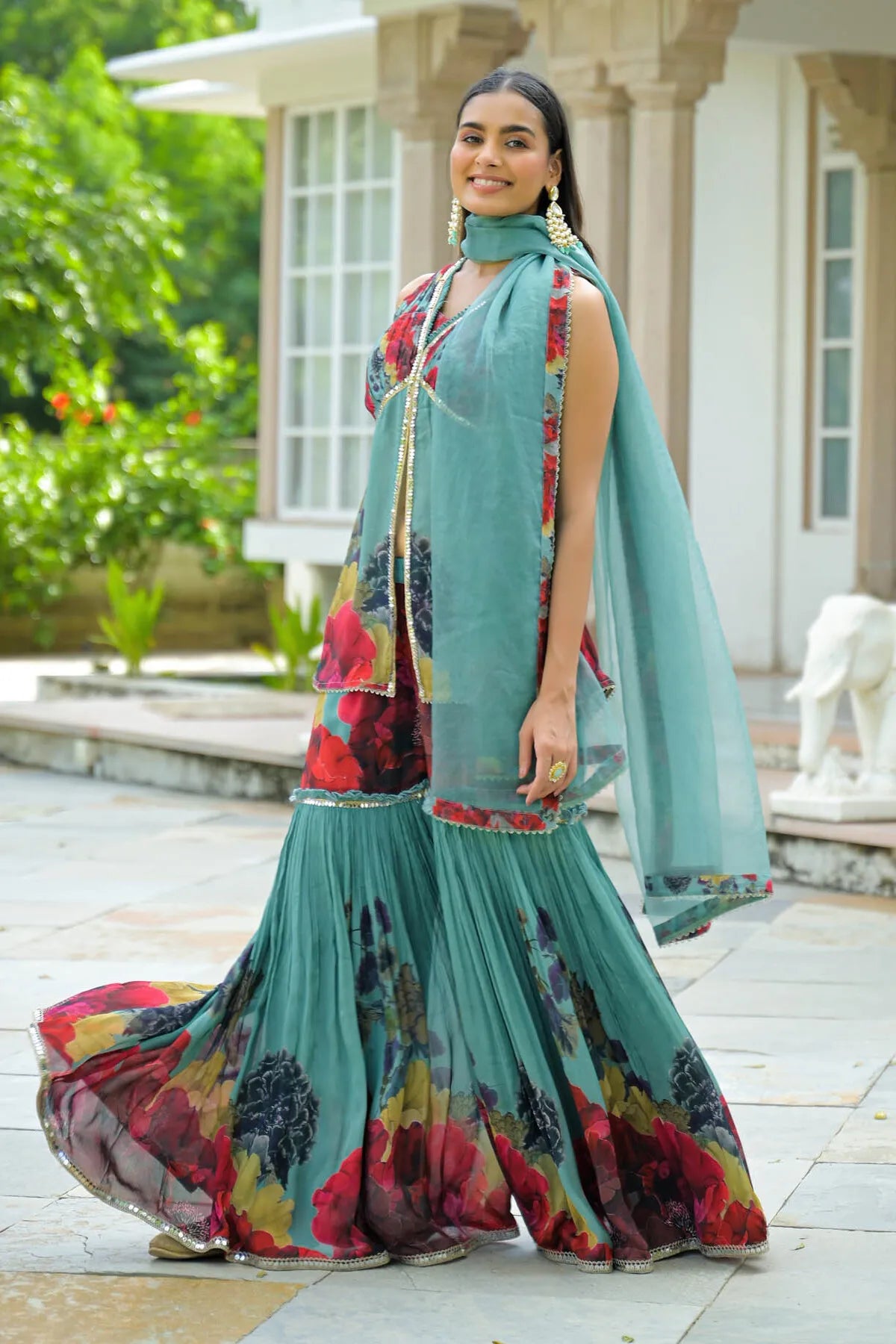 Woman in a traditional outfit with floral patterns standing outdoors.