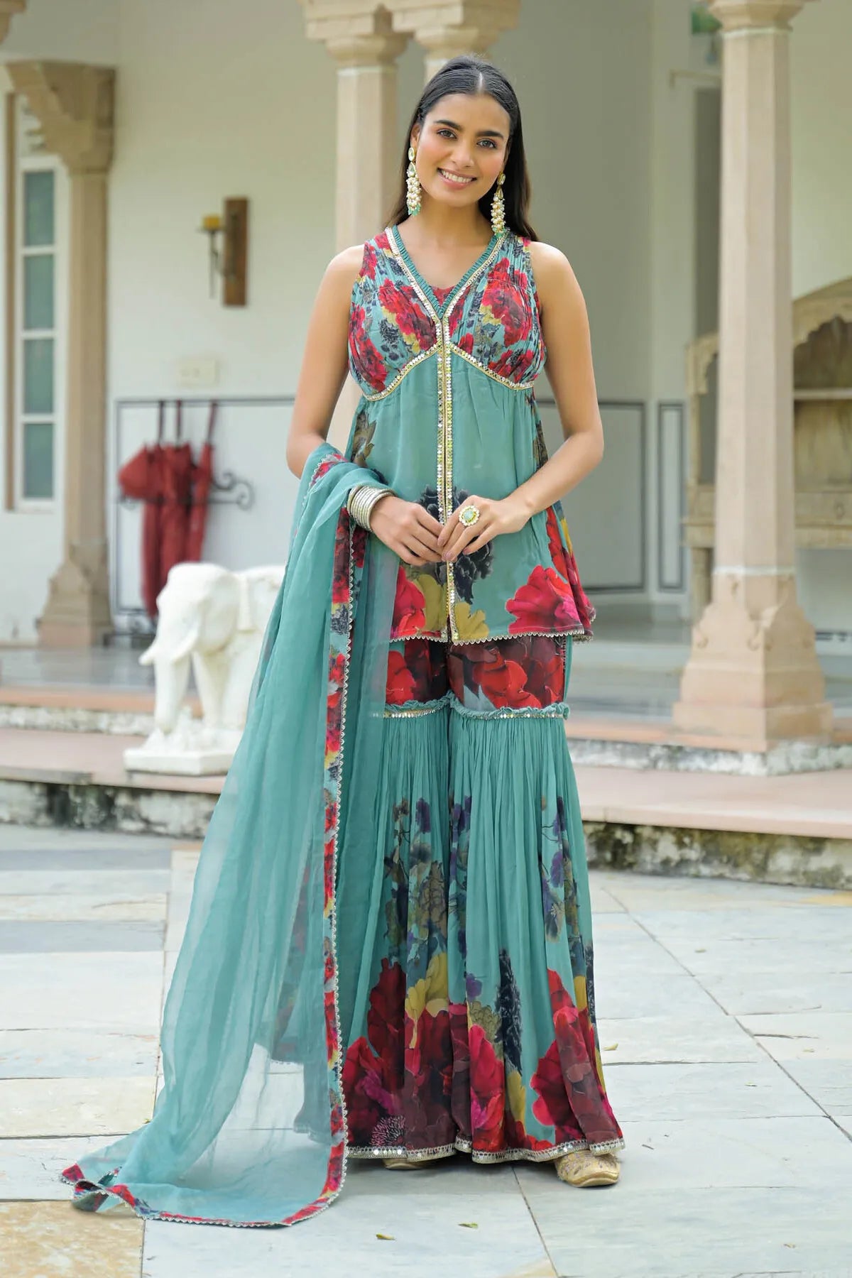 Woman in a traditional outfit with floral patterns standing outdoors.