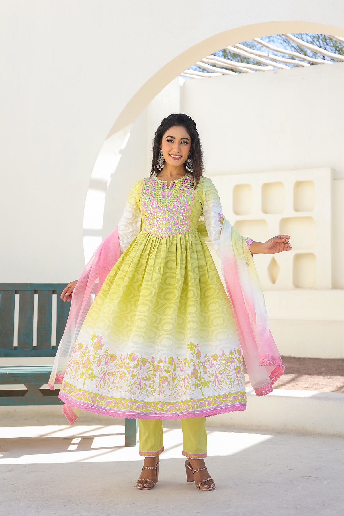 Woman wearing a yellow and pink traditional outfit in a bright room.