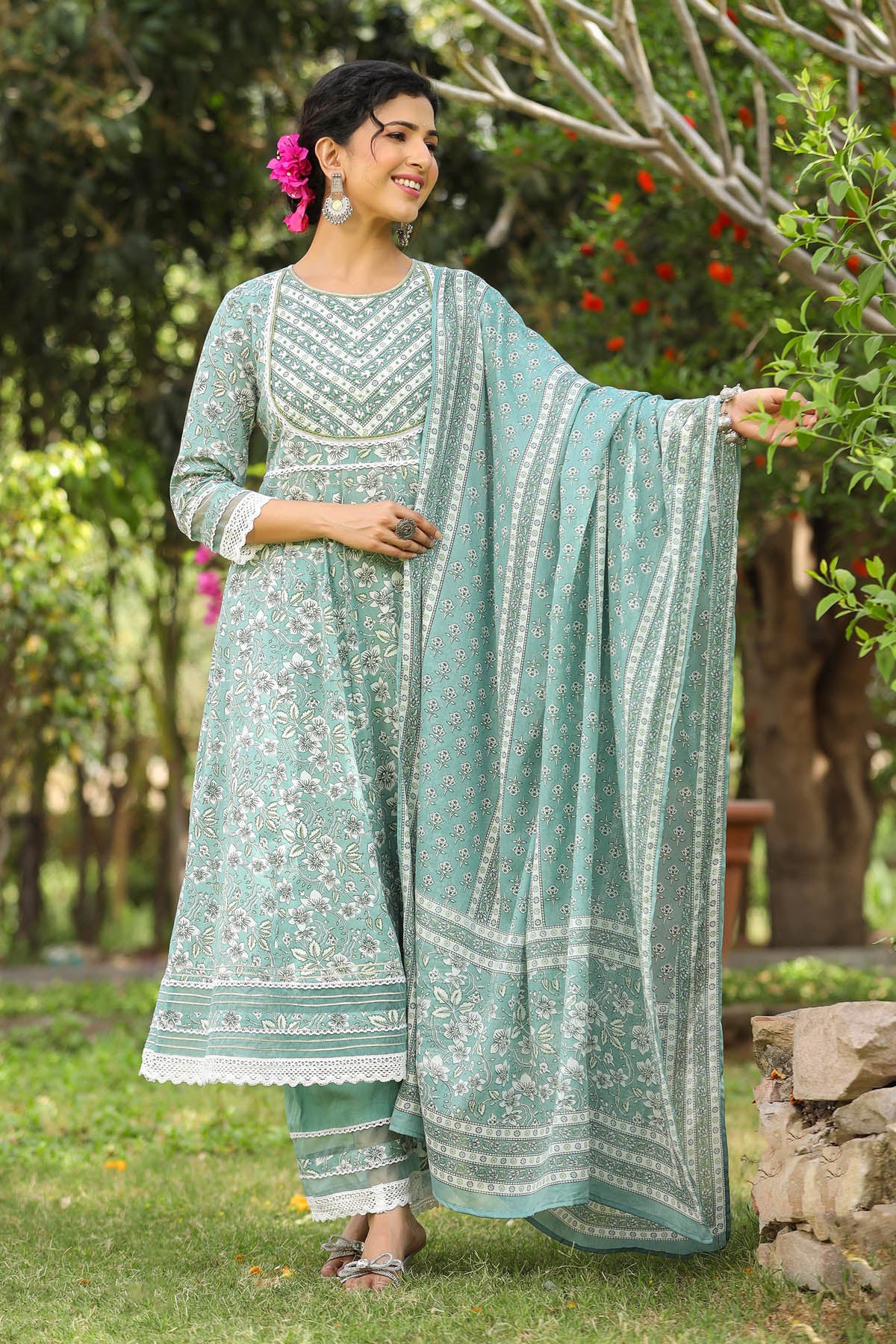 Woman in a light green traditional outfit with a matching dupatta, standing outdoors.