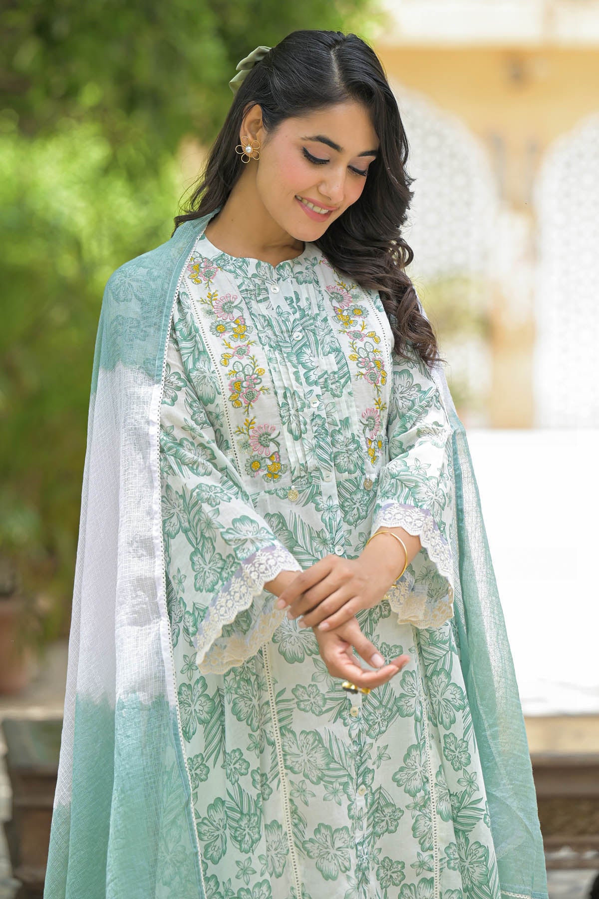 Woman wearing a light green and white traditional outfit with a floral pattern.