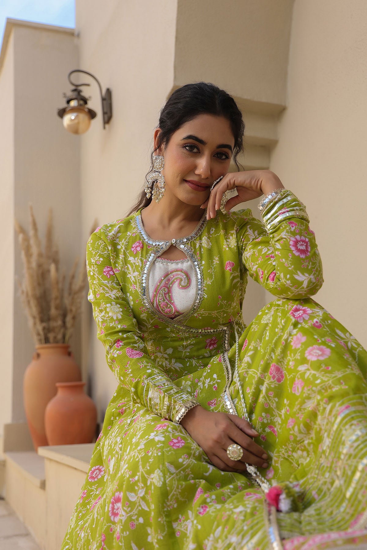 Woman in a green and pink traditional outfit standing outdoors.