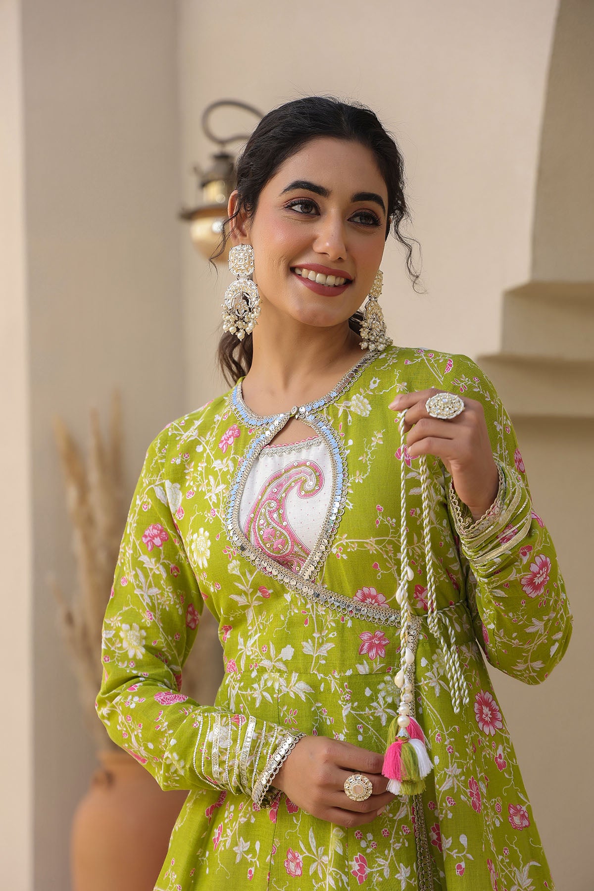 Woman in a green traditional outfit with floral patterns and jewelry.