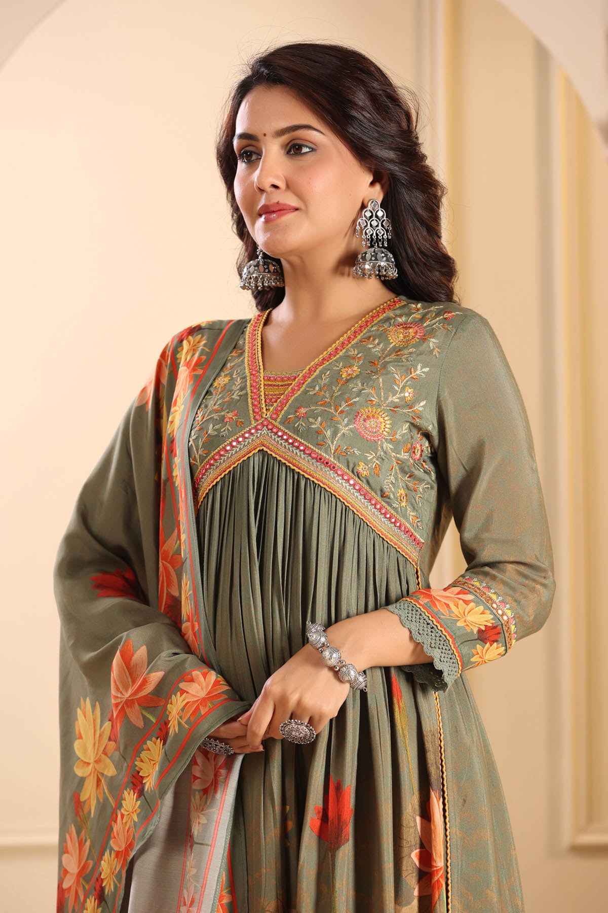 Woman wearing a traditional embroidered dress with a floral pattern against a neutral background