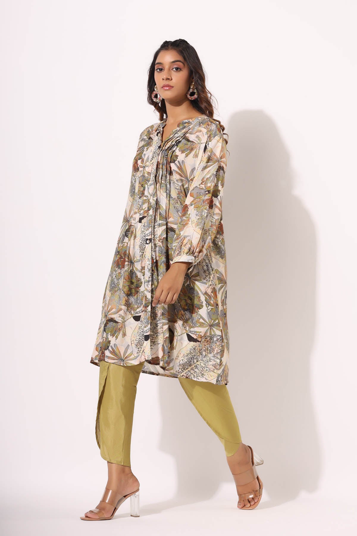 Woman wearing a floral dress and green pants on a white background