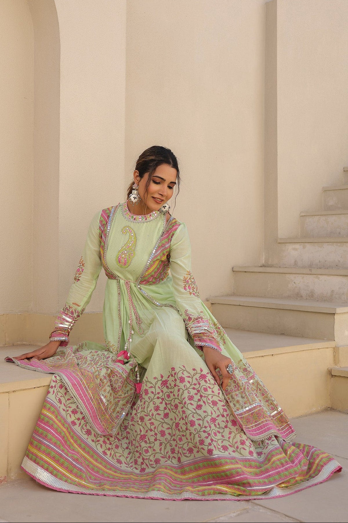 Woman in a traditional outfit sitting on a staircase in an elegant interior setting