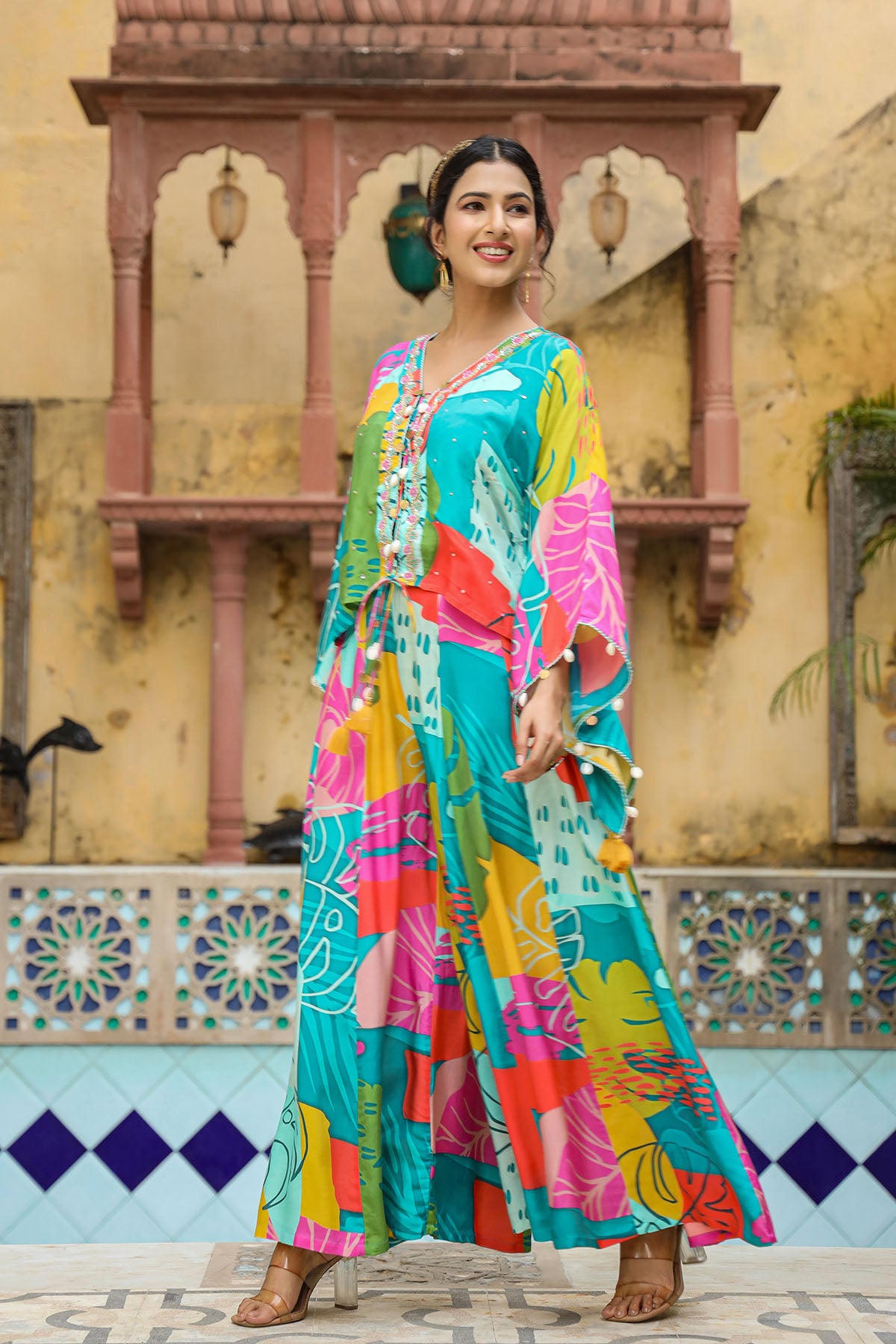 Woman in a colorful dress standing in front of a decorative wall.