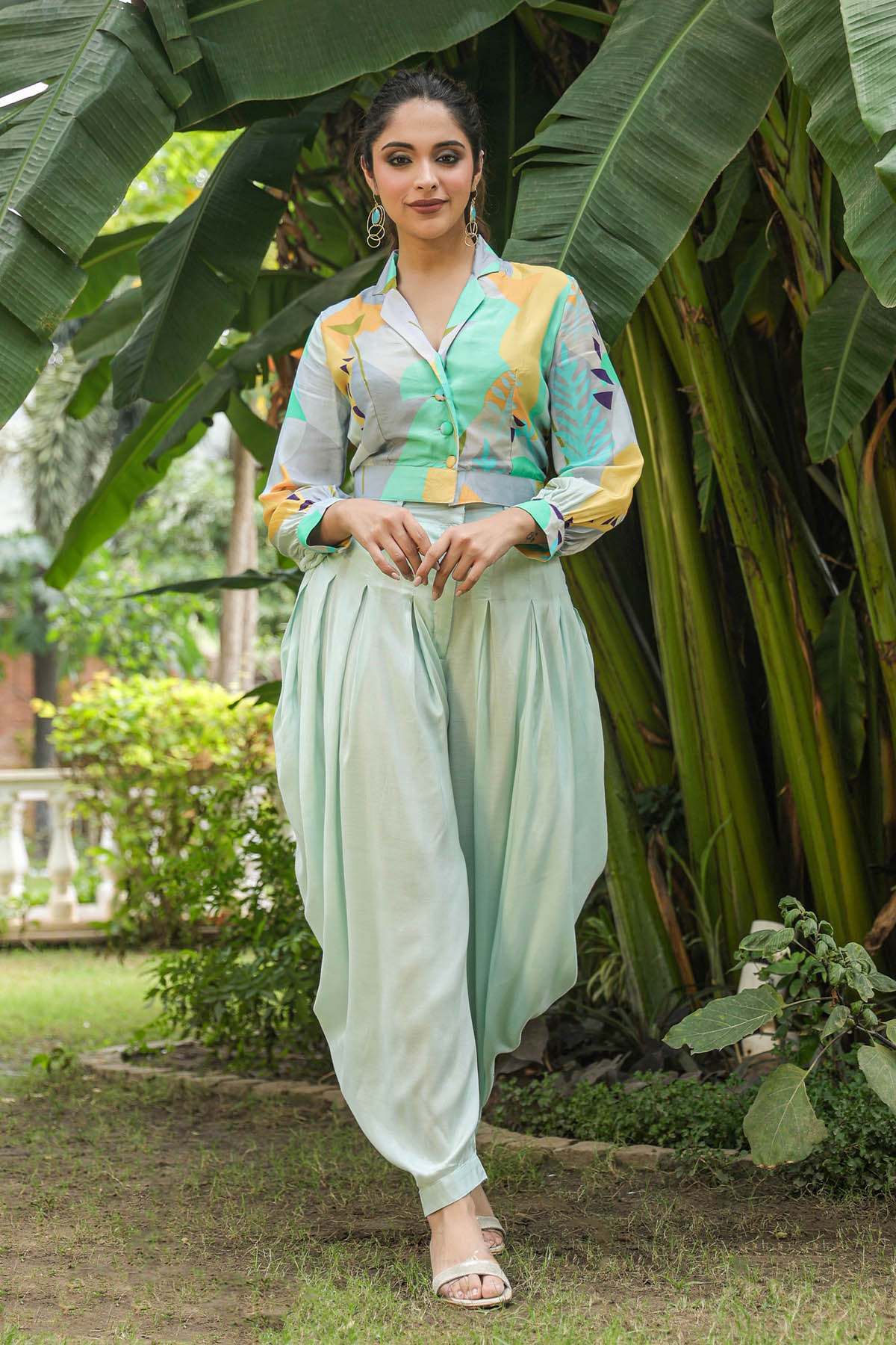 Woman in traditional outfit standing in a garden with greenery