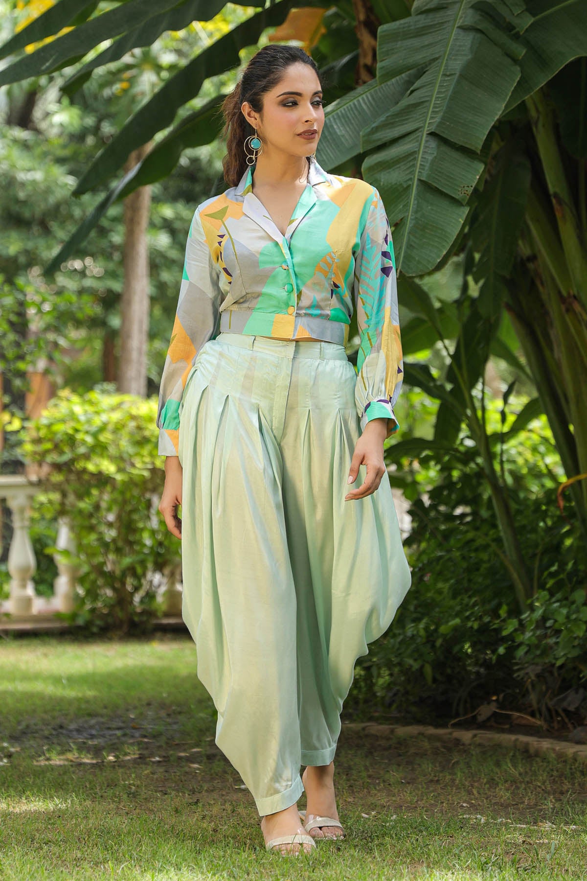 Woman in a colorful outfit standing in a garden with greenery