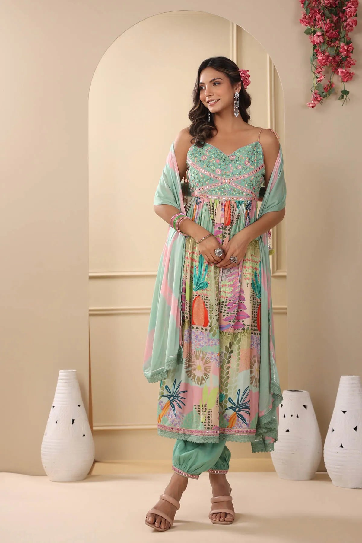 Woman wearing a colorful traditional outfit with a floral design in a decorated room.