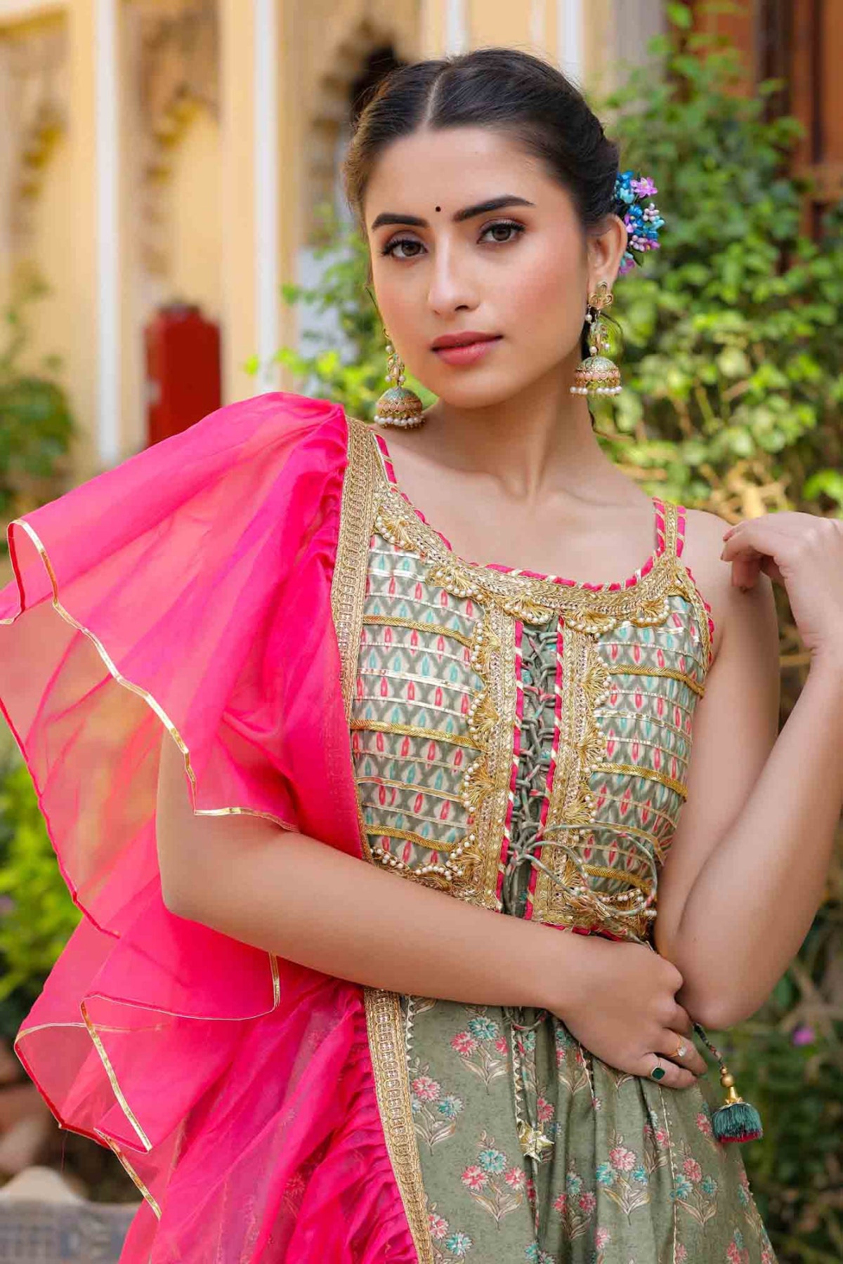 Woman in traditional attire with a pink dupatta against a blurred outdoor background