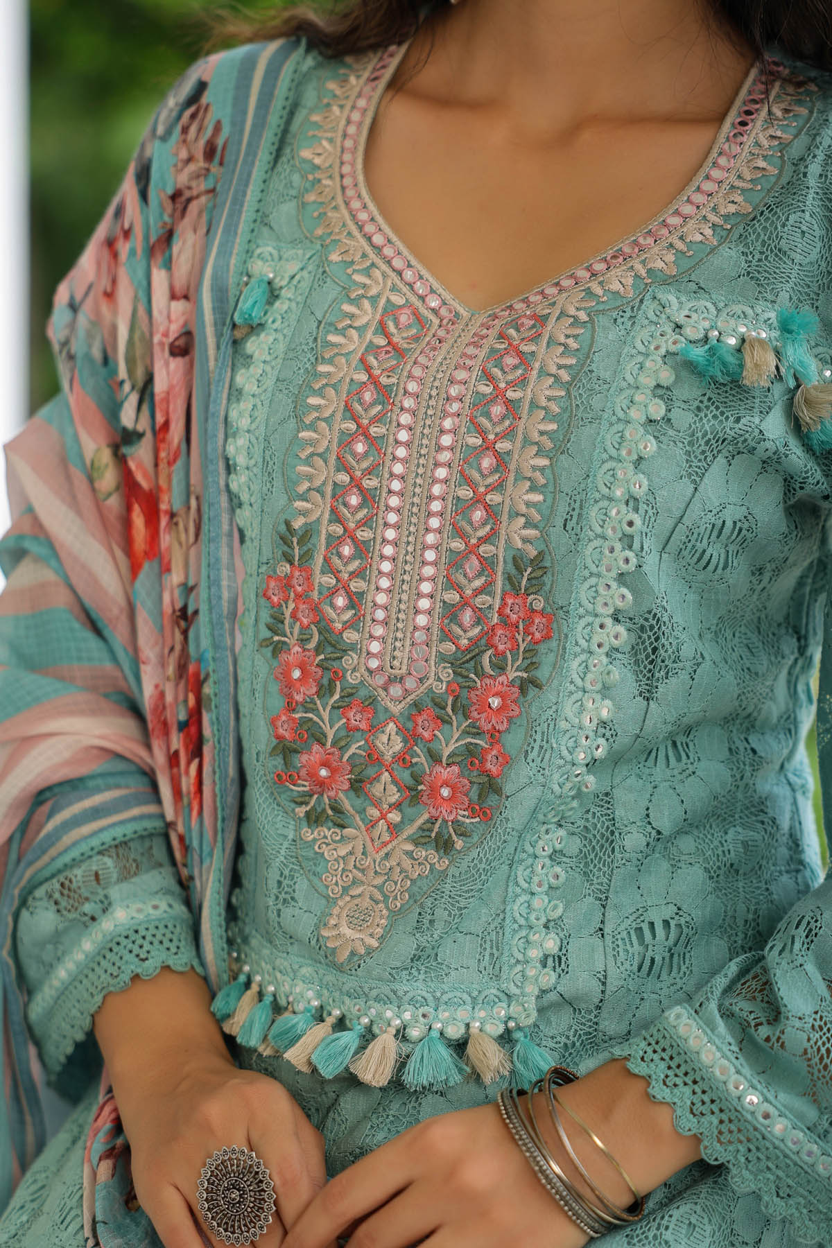 Close-up of a teal embroidered garment with floral patterns