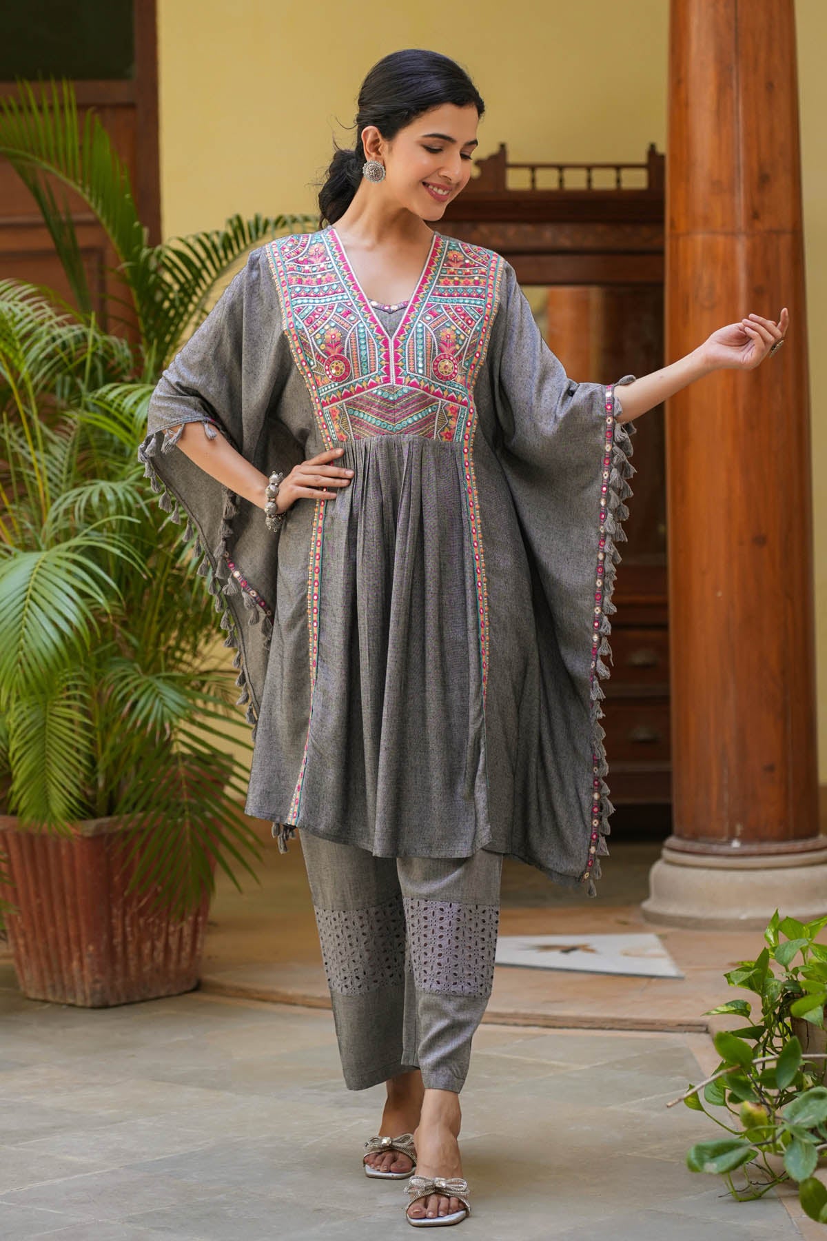 Woman in a traditional outfit standing in a room with plants