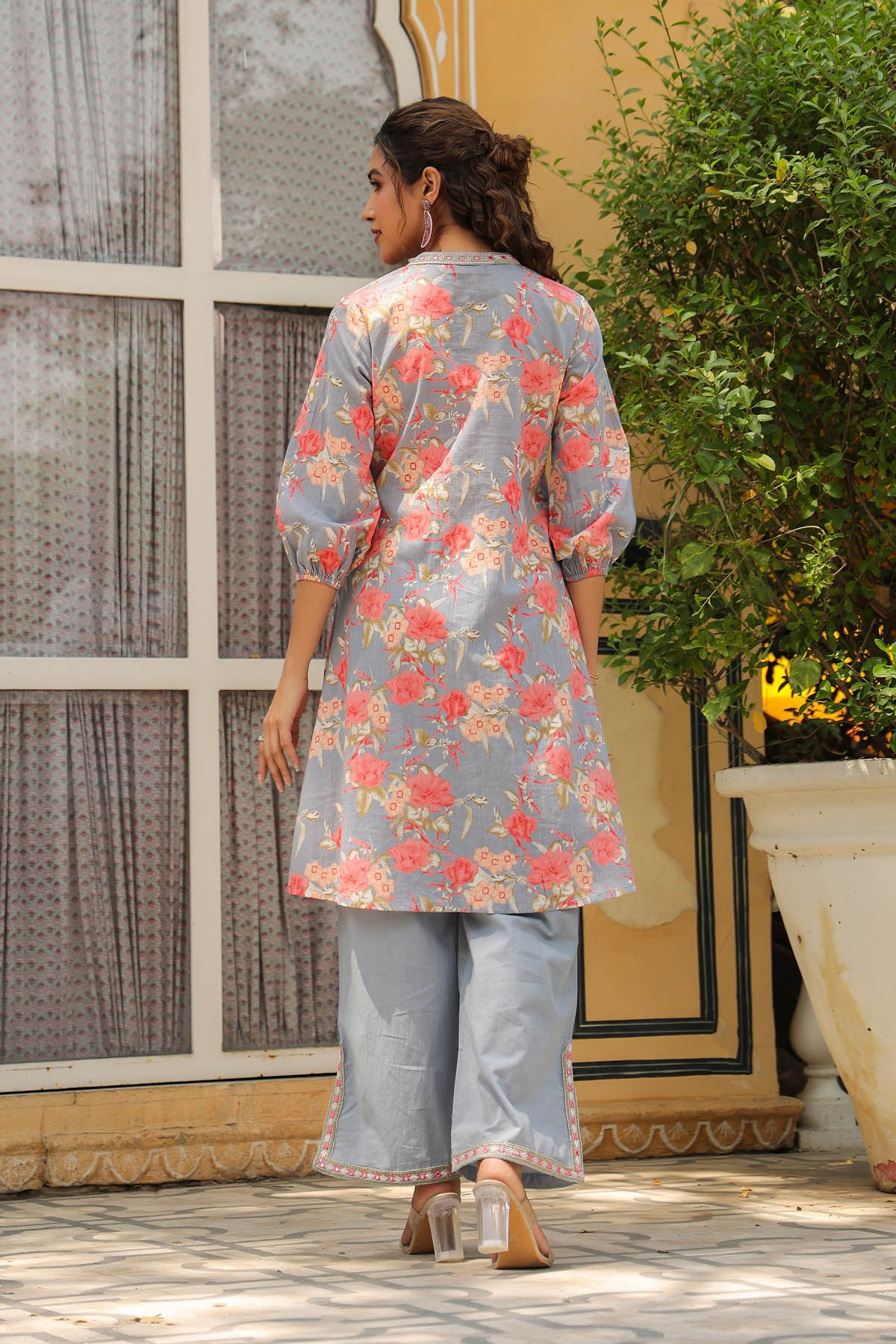Woman wearing a floral kurta with palazzo pants standing outdoors.