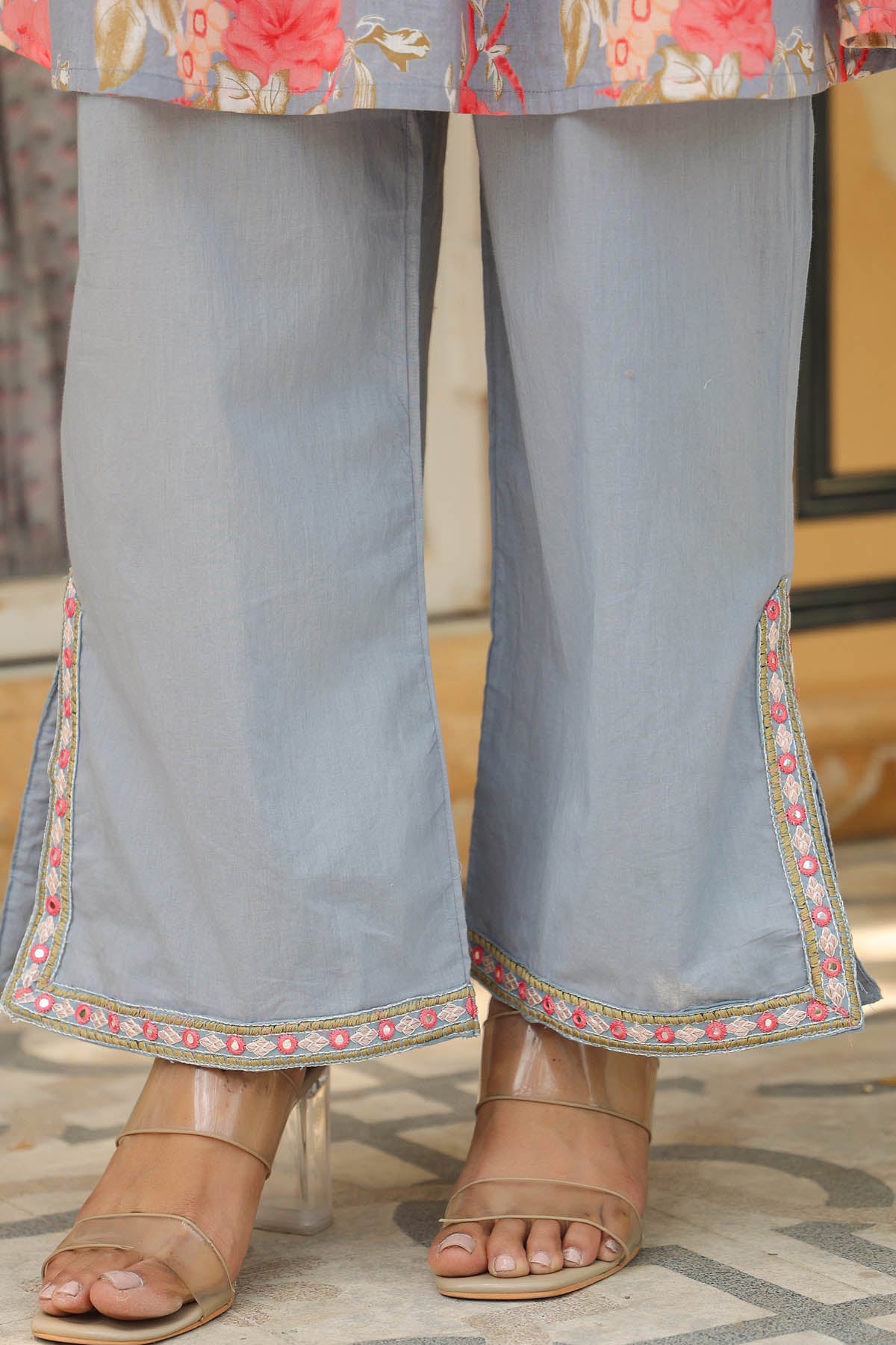 Light blue pants with floral embroidery at the bottom worn by a person.