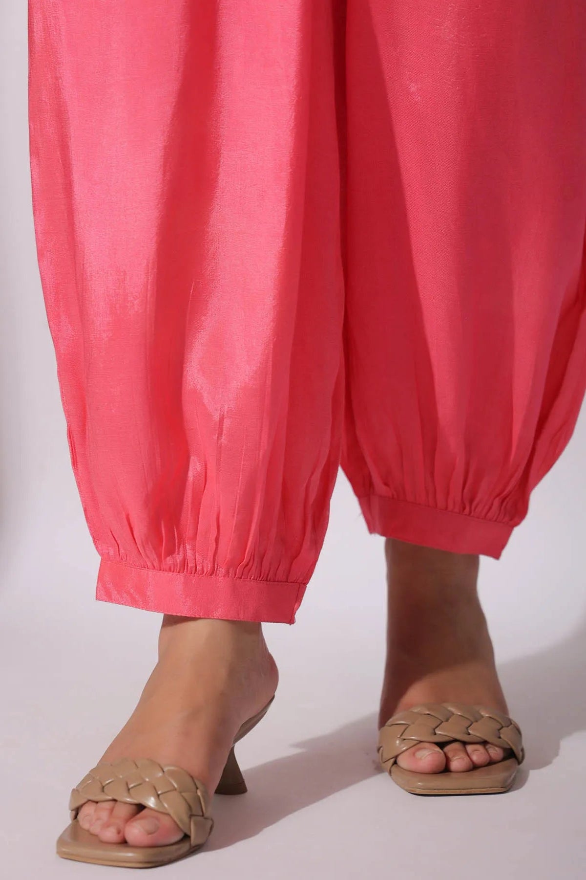 Person wearing pink pants and brown sandals on a white background