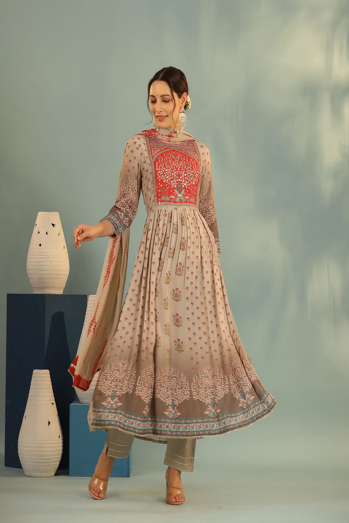 Woman wearing a traditional outfit with intricate designs in a studio setting