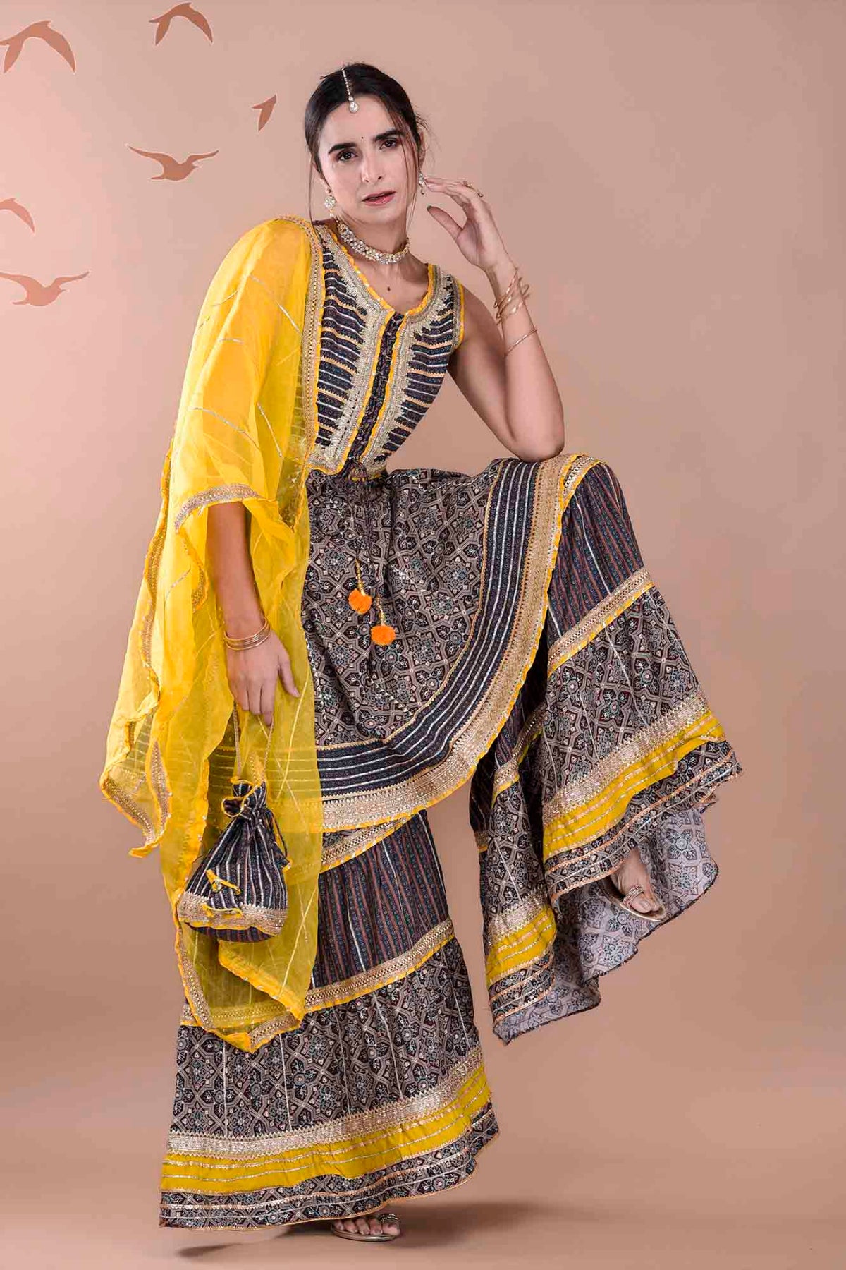Woman wearing a traditional outfit with a yellow dupatta on a beige background